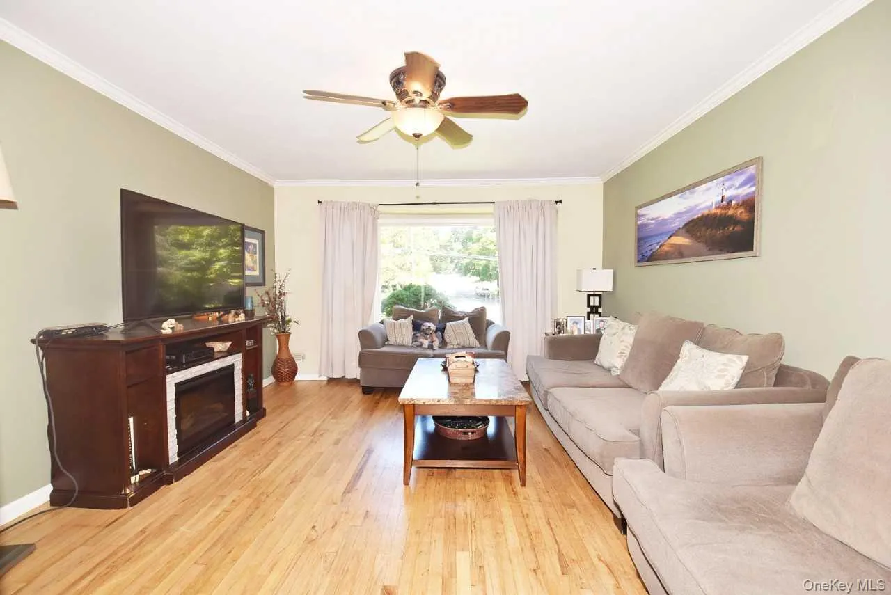 Wood-finish flooring, crown molding, and a ceiling fan with light fixture Wood-finish flooring, crown molding, and a ceiling fan with light fixture