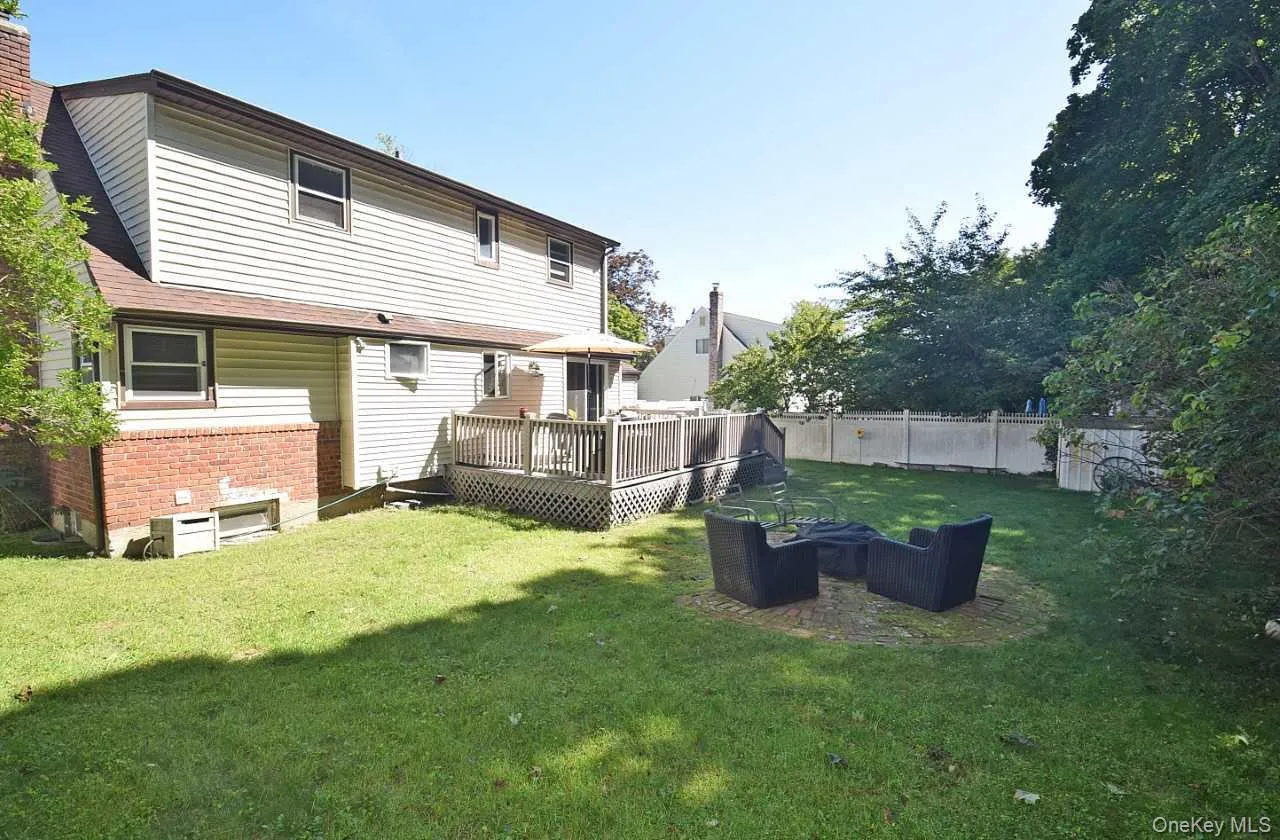 Expansive backyard featuring a manicured lawn, a raised deck, and a privacy fence Expansive backyard featuring a manicured lawn, a raised deck, and a privacy fence