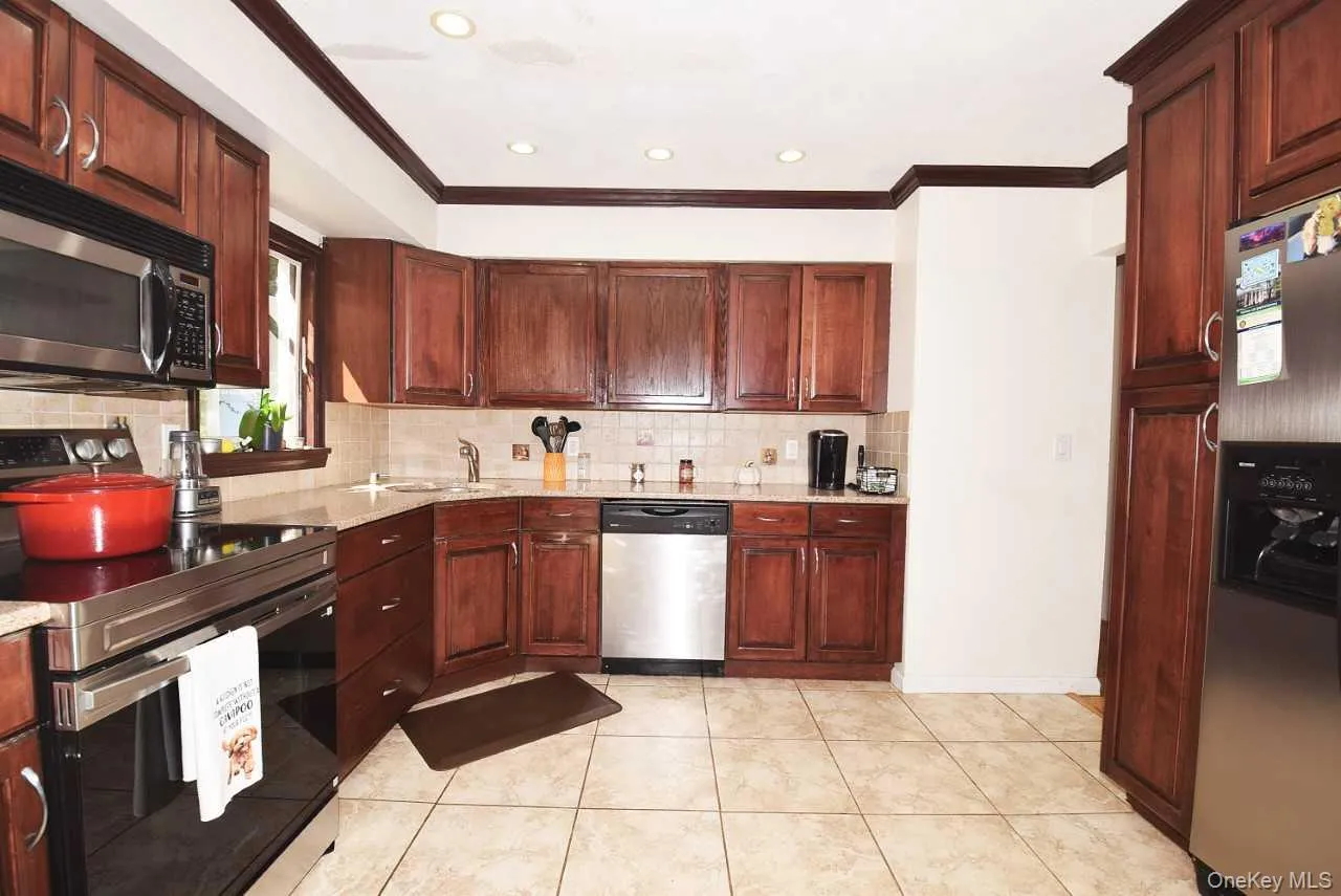 Kitchen featuring wood-finish cabinetry, stainless steel appliances, light-toned tiled flooring, and recessed ceiling lighting Kitchen featuring wood-finish cabinetry, stainless steel appliances, light-toned tiled flooring, and recessed ceiling lighting