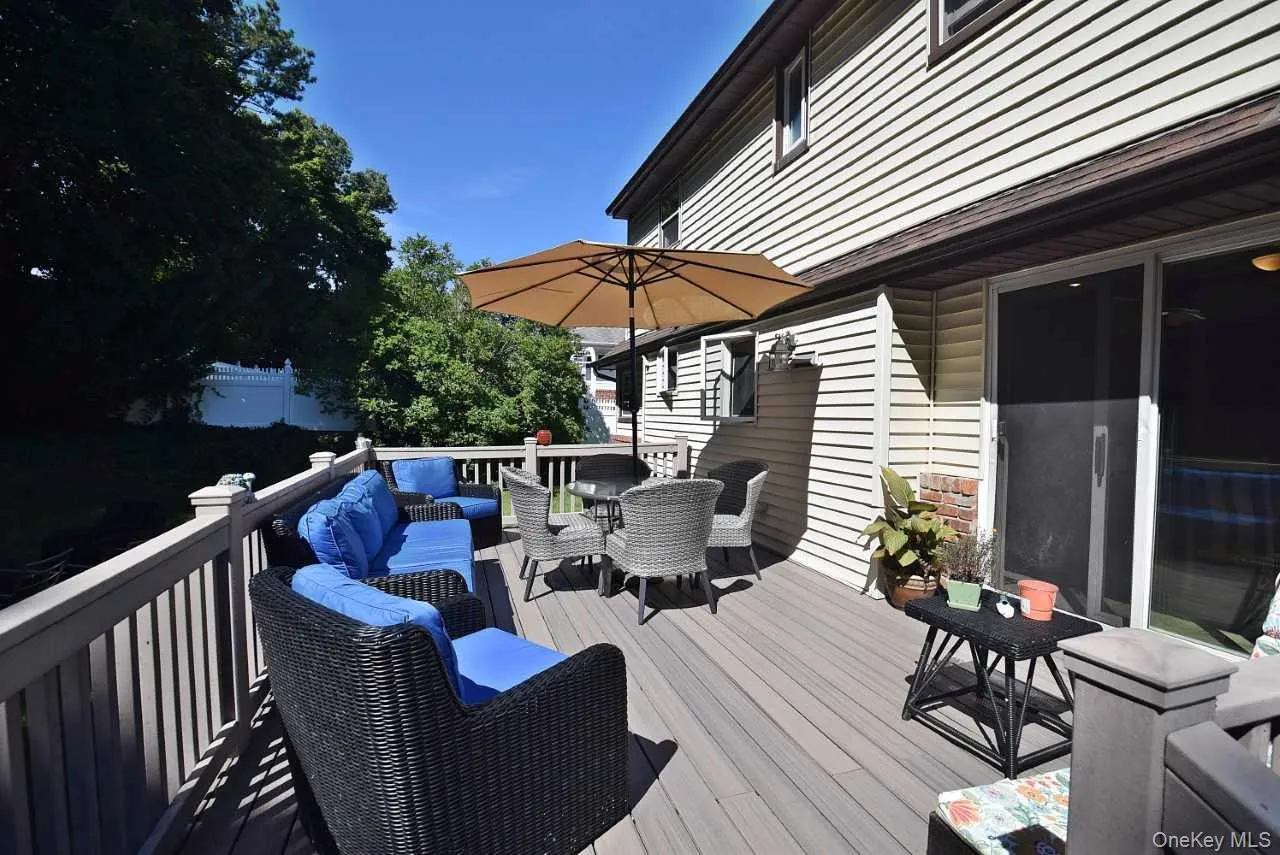 Expansive outdoor deck featuring composite decking, white railing, and direct access to the interior via sliding glass doors Expansive outdoor deck featuring composite decking, white railing, and direct access to the interior via sliding glass doors