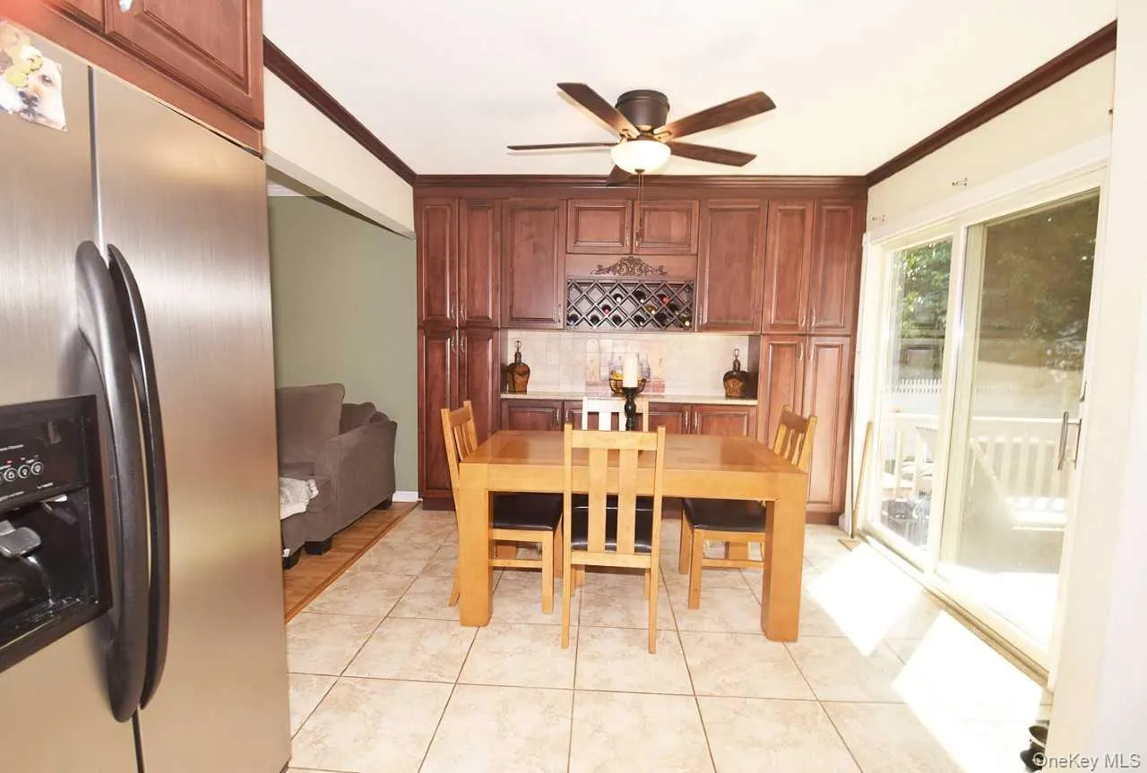 Recessed panel wood cabinetry, tile flooring, glass sliding door, ceiling fan with integrated lighting, and a built-in wine rack Recessed panel wood cabinetry, tile flooring, glass sliding door, ceiling fan with integrated lighting, and a built-in wine rack