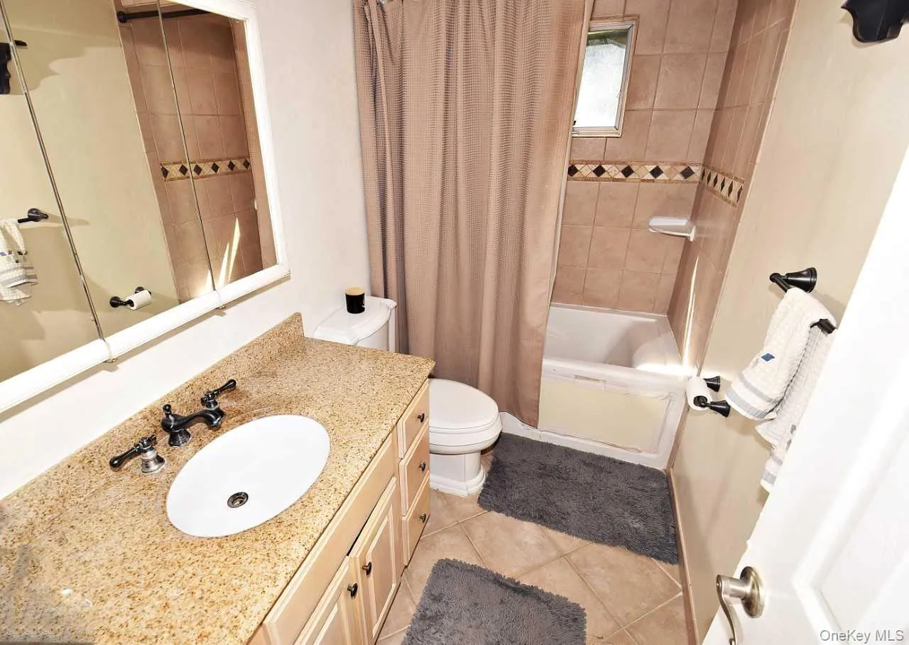Vanity with stone-finish countertop and oval undermount sink, built-in medicine cabinet, ceramic wall tiling, and a built-in tub Vanity with stone-finish countertop and oval undermount sink, built-in medicine cabinet, ceramic wall tiling, and a built-in tub