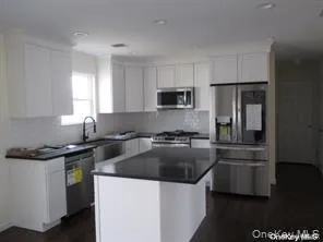 Kitchen featuring stainless steel appliances, white cabinets, dark countertops, and tasteful backsplash Kitchen featuring stainless steel appliances, white cabinets, dark countertops, and tasteful backsplash
