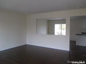 Empty room featuring baseboards and dark wood-style flooring Empty room featuring baseboards and dark wood-style flooring