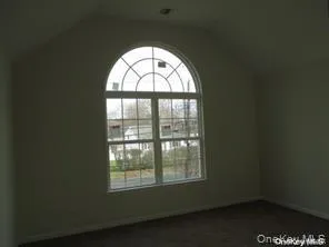 Unfurnished room featuring lofted ceiling and baseboards Unfurnished room featuring lofted ceiling and baseboards