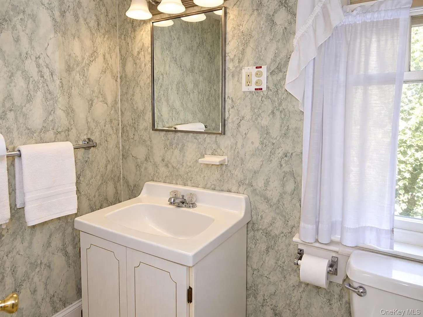 Vanity with integrated sink, wall-mounted mirror, overhead light fixture, and patterned wall covering Vanity with integrated sink, wall-mounted mirror, overhead light fixture, and patterned wall covering