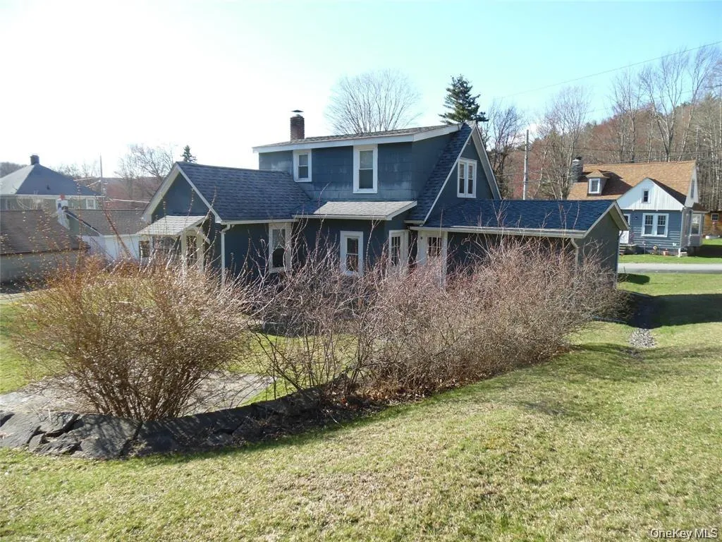 Two-story exterior with a dormer, dark blue siding, white window trim, and a shingled roof Two-story exterior with a dormer, dark blue siding, white window trim, and a shingled roof