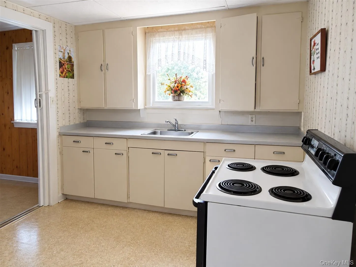 Kitchen featuring built-in cabinetry, laminate countertops, a stainless steel sink, and a white electric range Kitchen featuring built-in cabinetry, laminate countertops, a stainless steel sink, and a white electric range