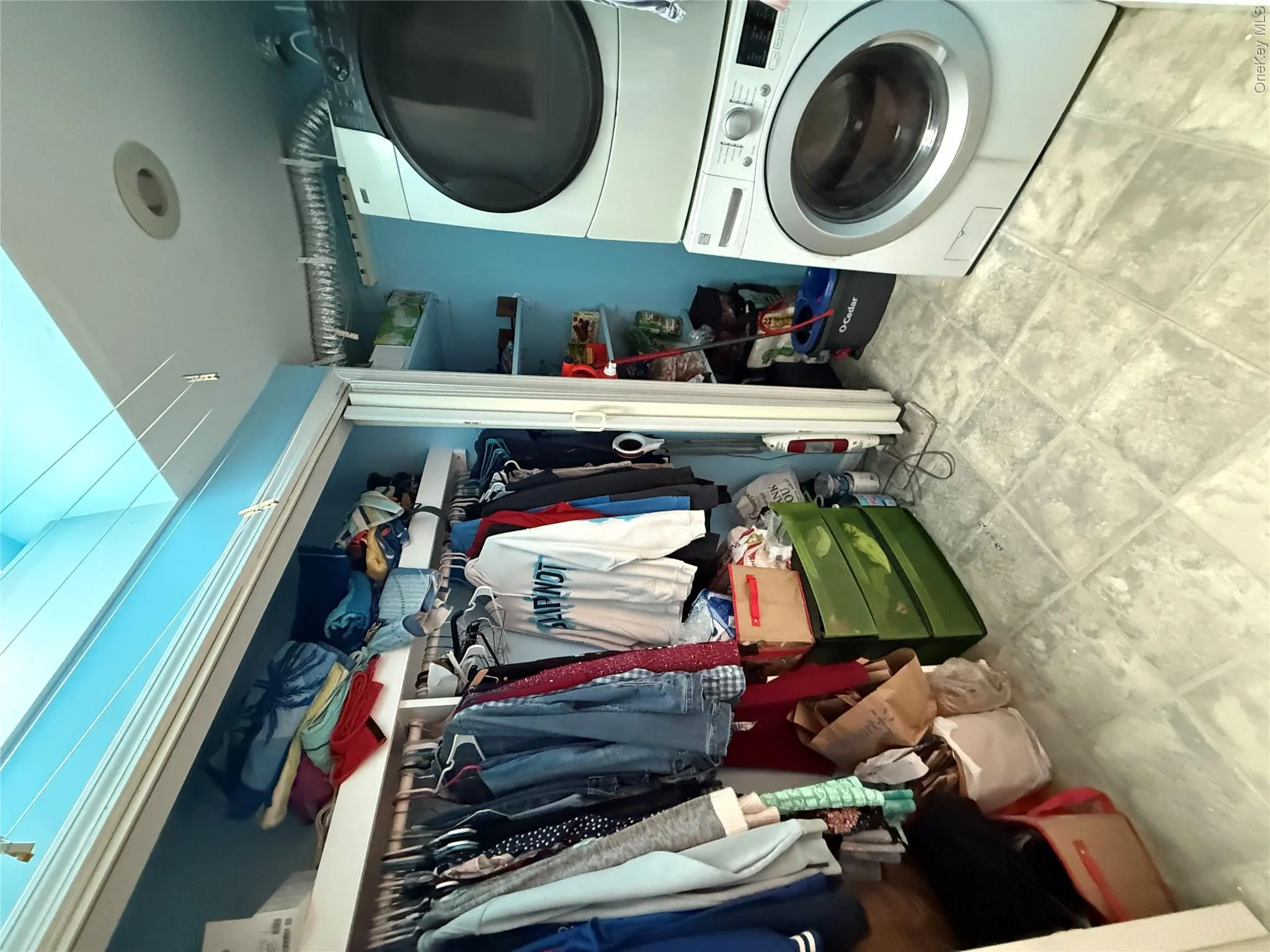 Laundry area featuring a stackable washer and dryer, tile flooring, built-in shelving, and recessed lighting Laundry area featuring a stackable washer and dryer, tile flooring, built-in shelving, and recessed lighting