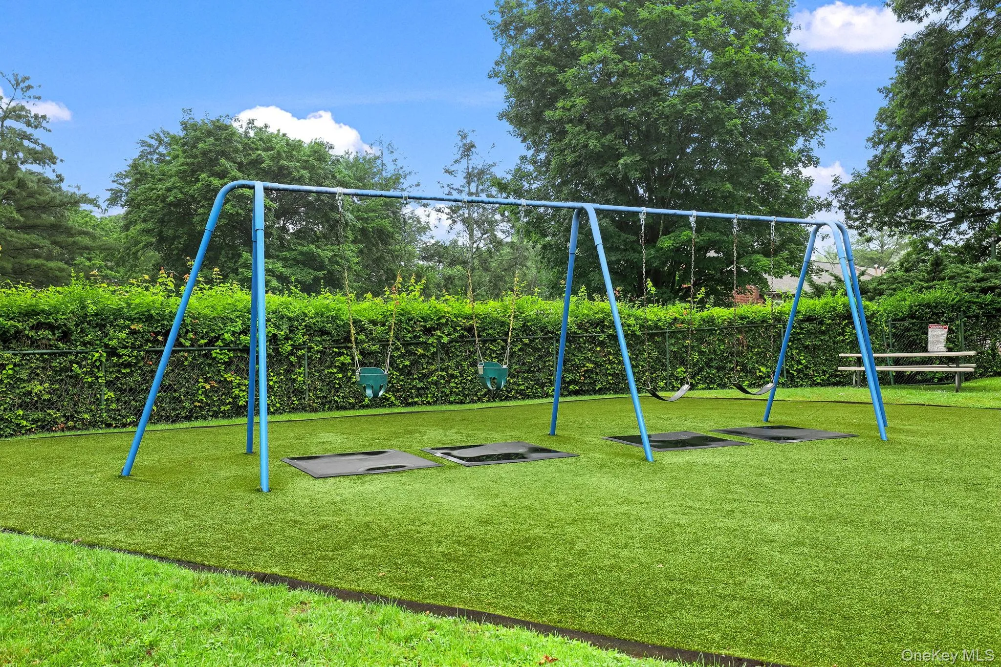 The playground has swing sets, and benches for sitting The playground has swing sets, and benches for sitting