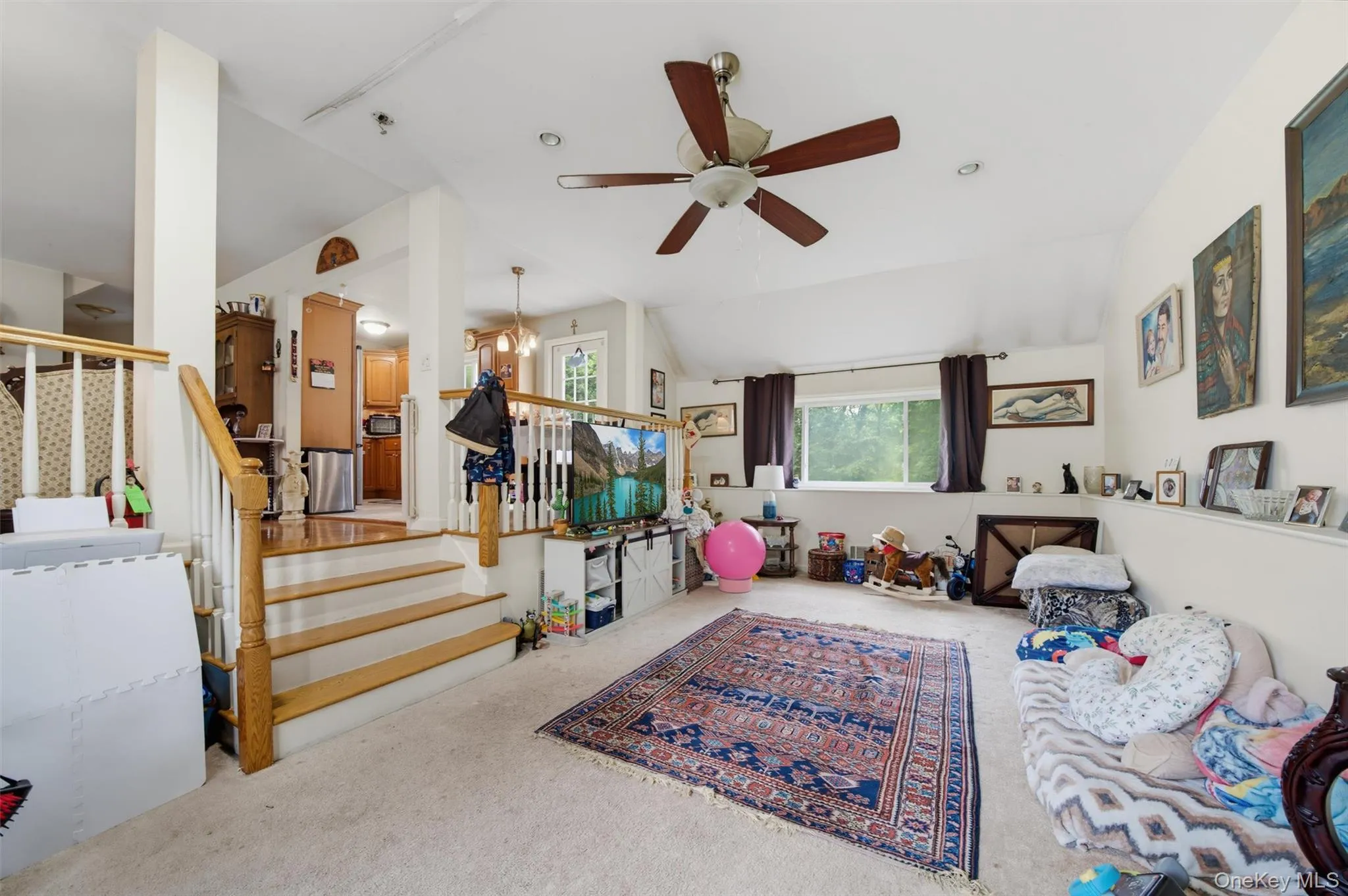 Carpeted living area with a vaulted ceiling, recessed lighting, and a ceiling fan Carpeted living area with a vaulted ceiling, recessed lighting, and a ceiling fan