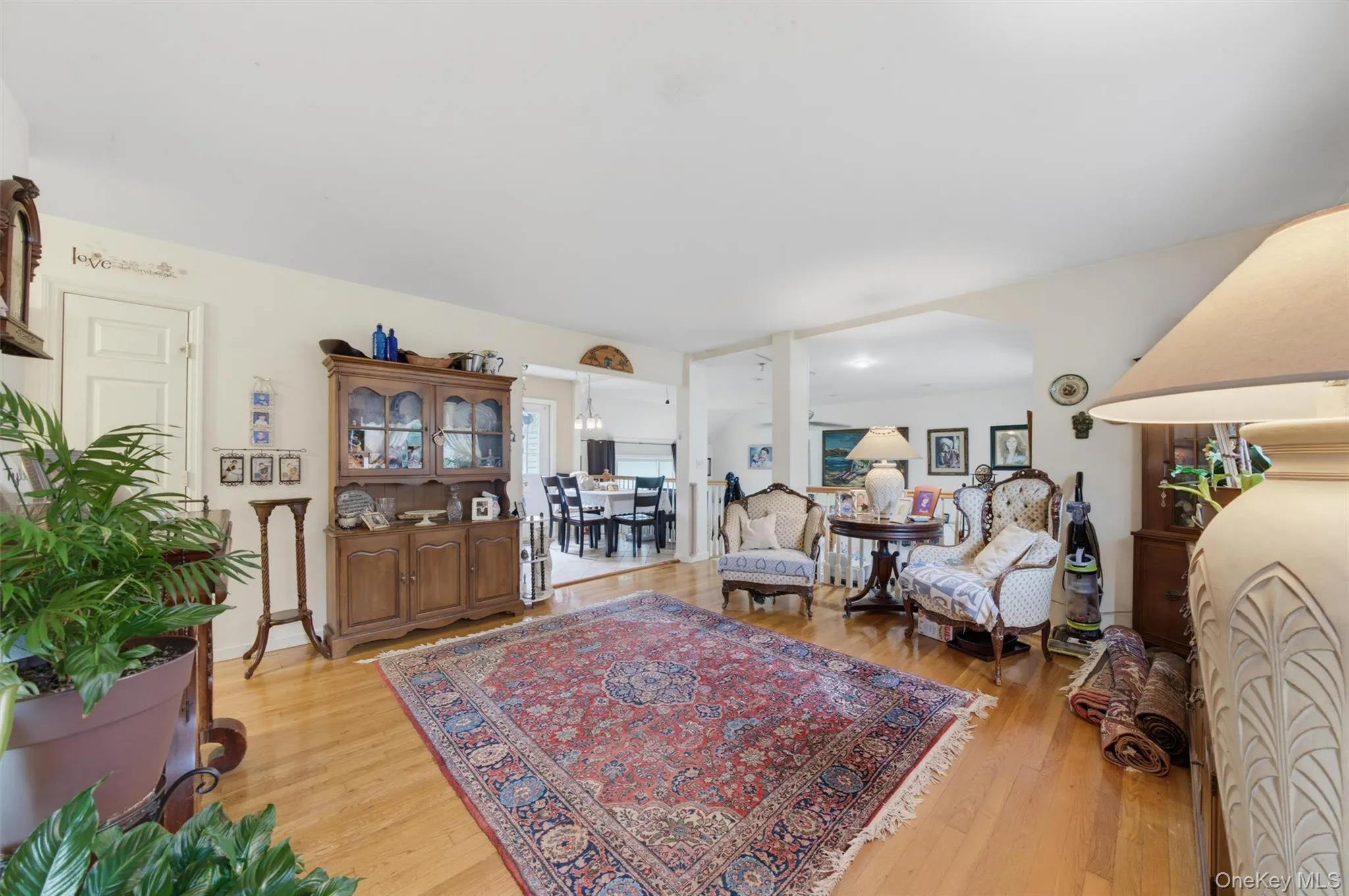 Wood-finish flooring throughout, with a wide opening leading to a dining area with a chandelier Wood-finish flooring throughout, with a wide opening leading to a dining area with a chandelier