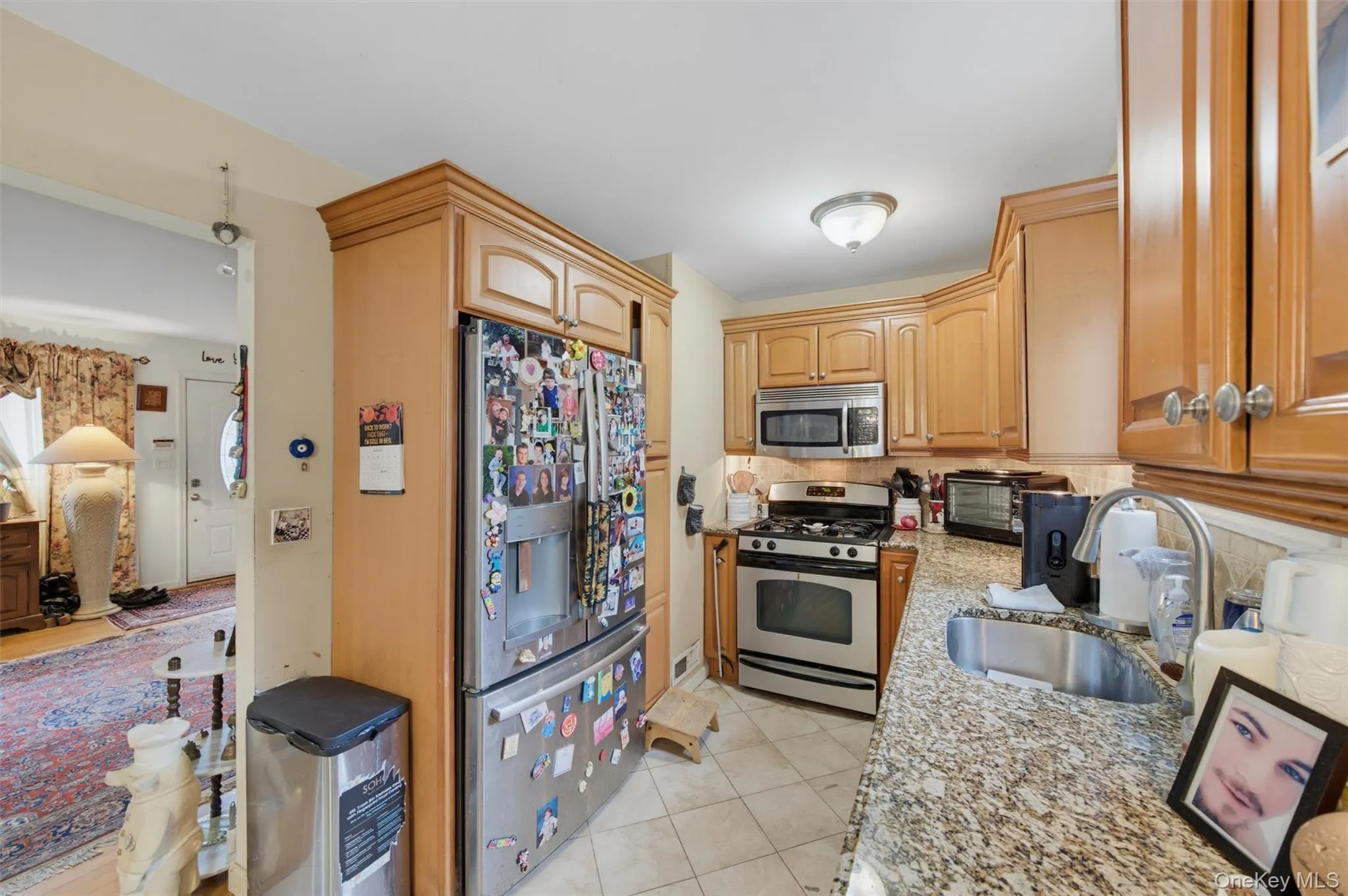 Kitchen featuring light wood cabinetry, stainless steel appliances, granite countertops, and tile flooring Kitchen featuring light wood cabinetry, stainless steel appliances, granite countertops, and tile flooring