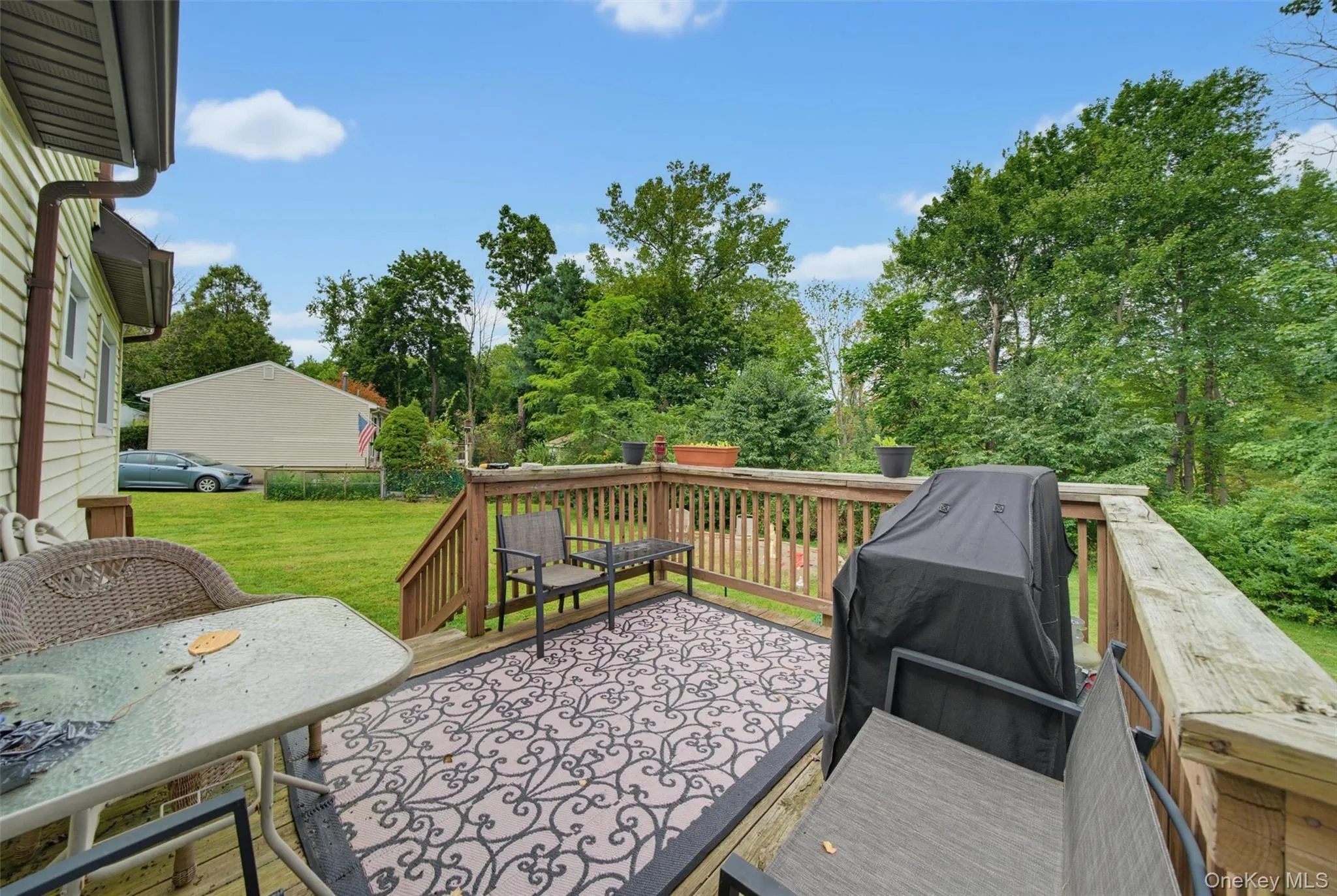 Expansive wood deck with stairs, featuring wood railings and a green yard Expansive wood deck with stairs, featuring wood railings and a green yard