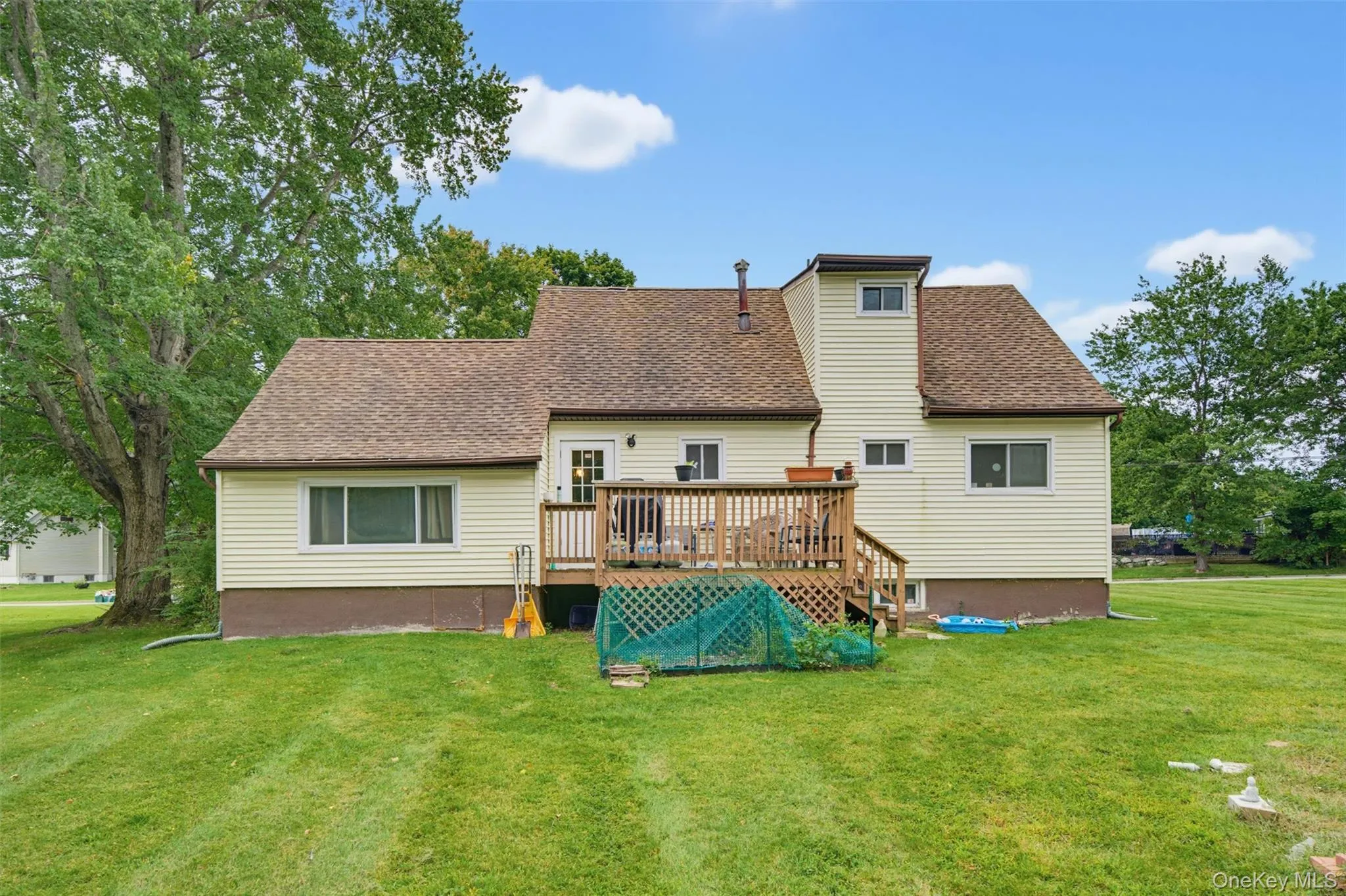 Expansive green lawn with mature trees and a multi-level wood deck Expansive green lawn with mature trees and a multi-level wood deck
