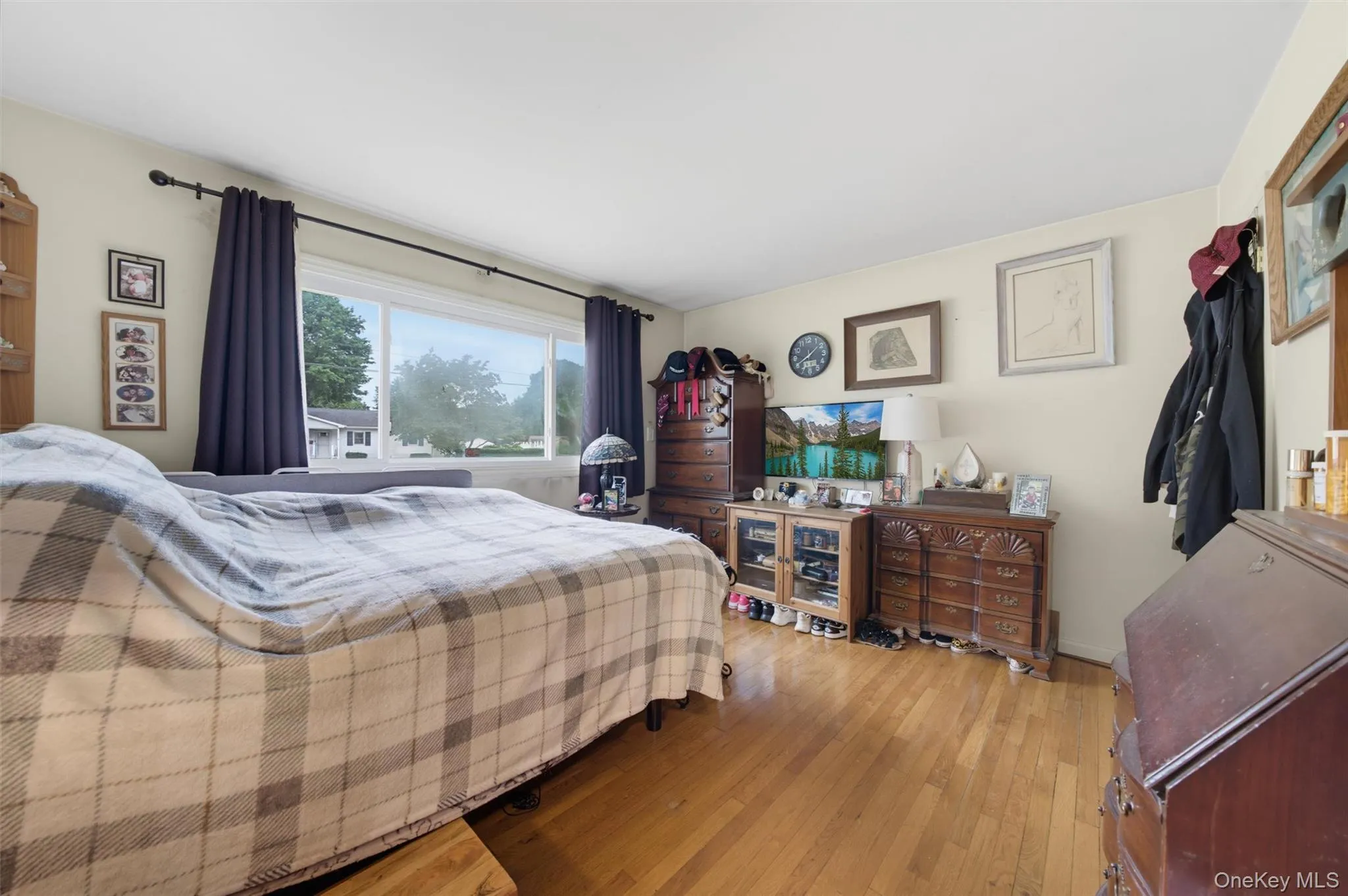 Wood-finish flooring with a large window featuring dark curtains Wood-finish flooring with a large window featuring dark curtains