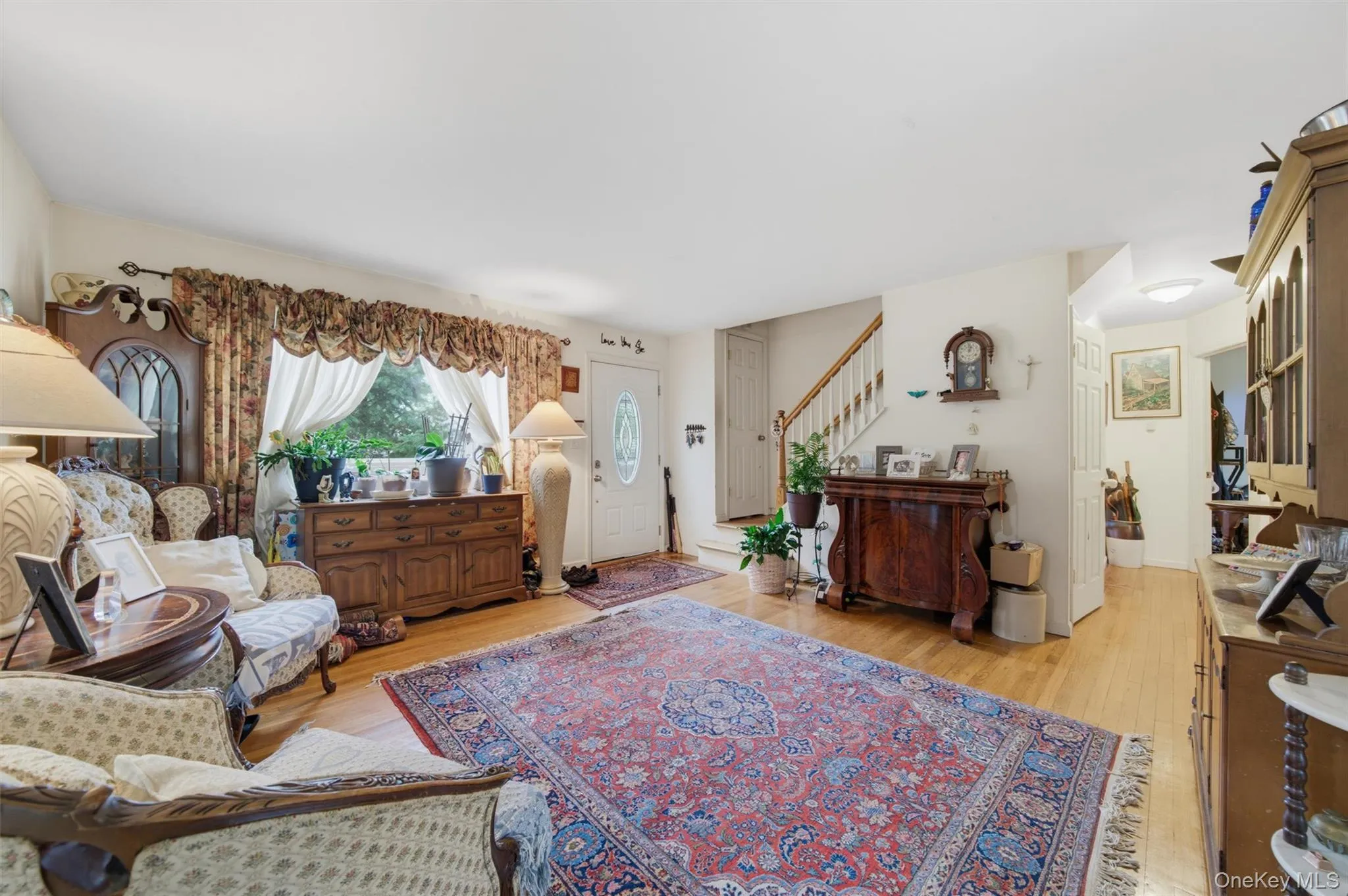 Hardwood flooring, a prominent front entry door, and a built-in staircase with a wood handrail Hardwood flooring, a prominent front entry door, and a built-in staircase with a wood handrail