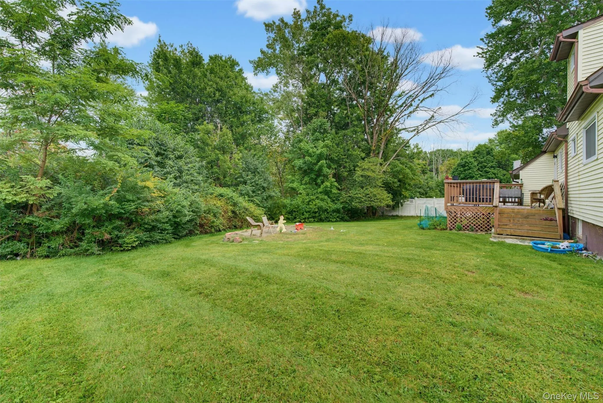 Expansive green lawn with mature "Privacy trees" and a wood-slatted deck Expansive green lawn with mature "Privacy trees" and a wood-slatted deck