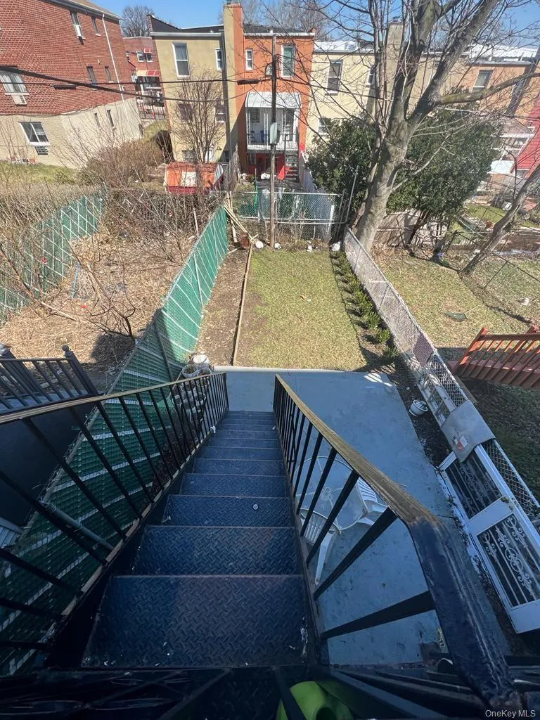 Metal staircase with diamond plate treads and black railings leading to a concrete landing and fenced backyard Metal staircase with diamond plate treads and black railings leading to a concrete landing and fenced backyard