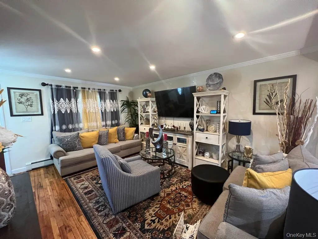 Hardwood flooring, recessed ceiling lighting, crown molding, and white wall finishes Hardwood flooring, recessed ceiling lighting, crown molding, and white wall finishes