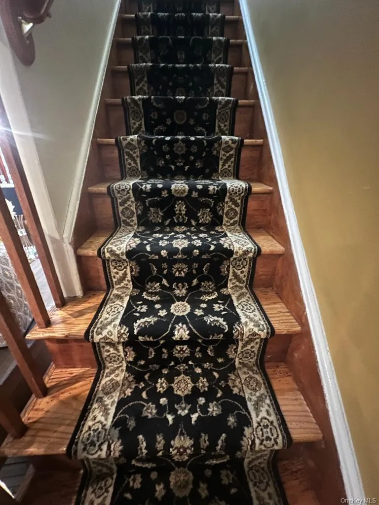 Wood-finish staircase with a decorative patterned runner Wood-finish staircase with a decorative patterned runner