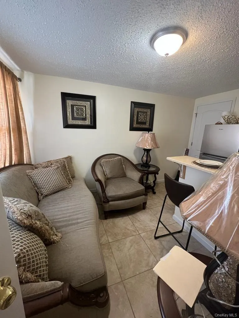 Basement area, tile flooring, recessed ceiling lighting, light-toned walls, built-in breakfast bar, and a stainless steel refrigerator Basement area, tile flooring, recessed ceiling lighting, light-toned walls, built-in breakfast bar, and a stainless steel refrigerator