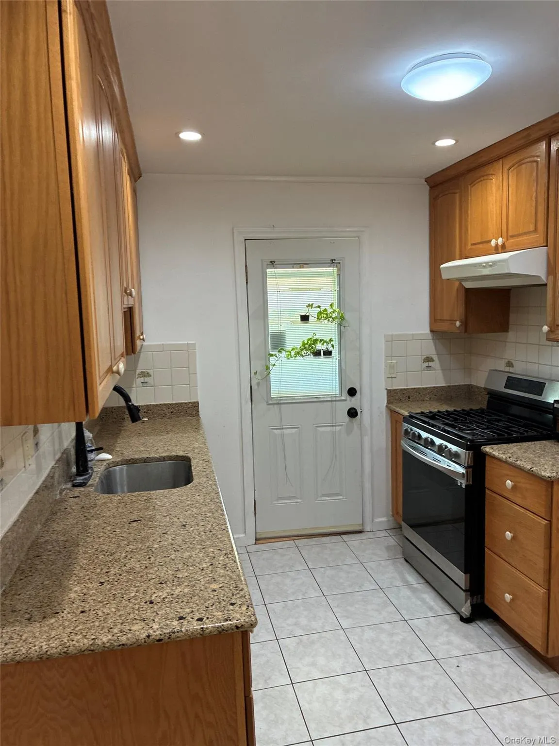 Kitchen featuring wood cabinetry, stone countertops, stainless steel gas range, and tile flooring Kitchen featuring wood cabinetry, stone countertops, stainless steel gas range, and tile flooring