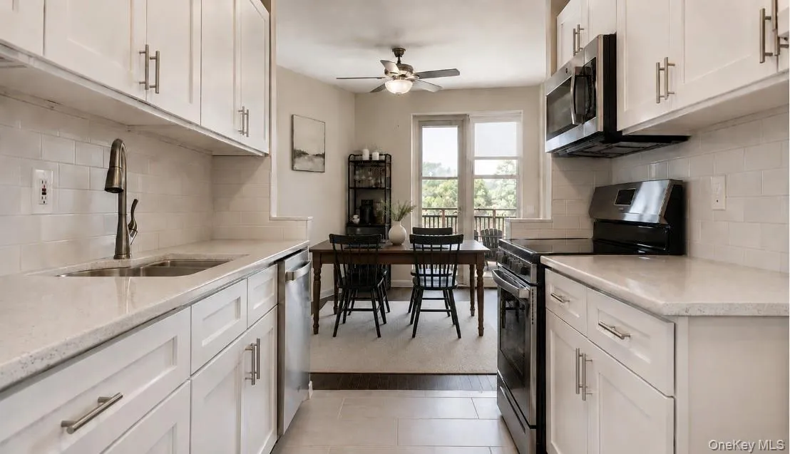 Updated galley kitchen featuring white shaker cabinetry, subway tile backsplash, stainless steel appliances and ample counter space, conveniently situated beside the dining area. Updated galley kitchen featuring white shaker cabinetry, subway tile backsplash, stainless steel appliances and ample counter space, conveniently situated beside the dining area.