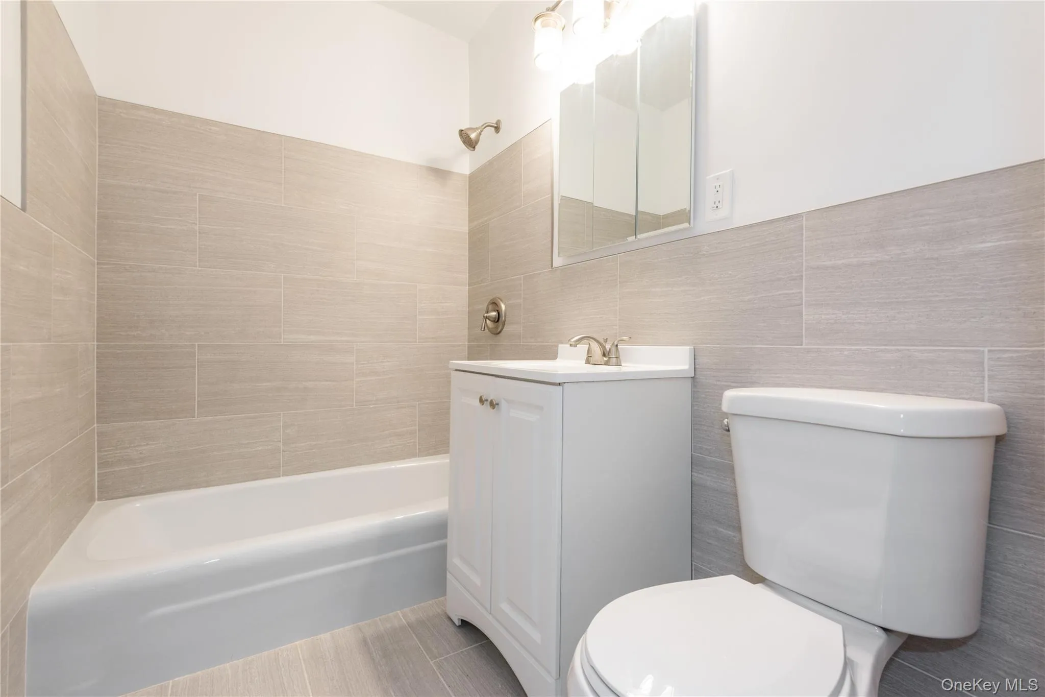 Updated main bathroom featuring a tub and shower combination, modern neutral tilework and a crisp white vanity. Updated main bathroom featuring a tub and shower combination, modern neutral tilework and a crisp white vanity.