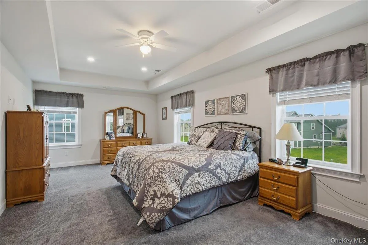 Tray ceiling featuring recessed lighting and a ceiling fan, broad windows, and soft gray carpeting Tray ceiling featuring recessed lighting and a ceiling fan, broad windows, and soft gray carpeting