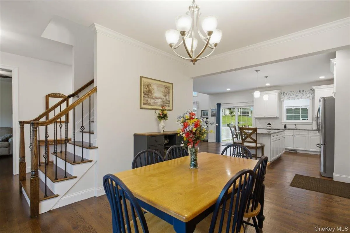 Hardwood flooring, elegant staircase with iron balusters, recessed lighting, white cabinetry, and stainless-steel appliances Hardwood flooring, elegant staircase with iron balusters, recessed lighting, white cabinetry, and stainless-steel appliances