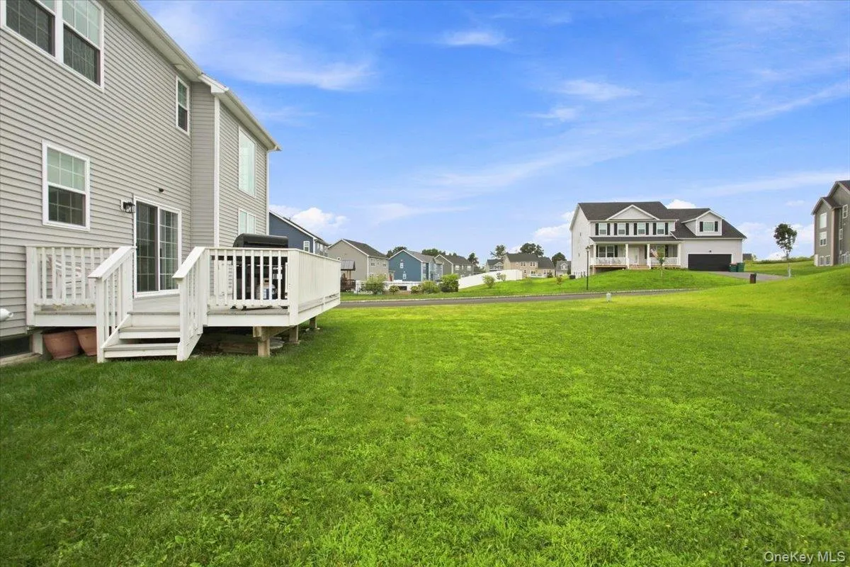 Expansive green lawn with a white wooden deck and sliding glass door access Expansive green lawn with a white wooden deck and sliding glass door access