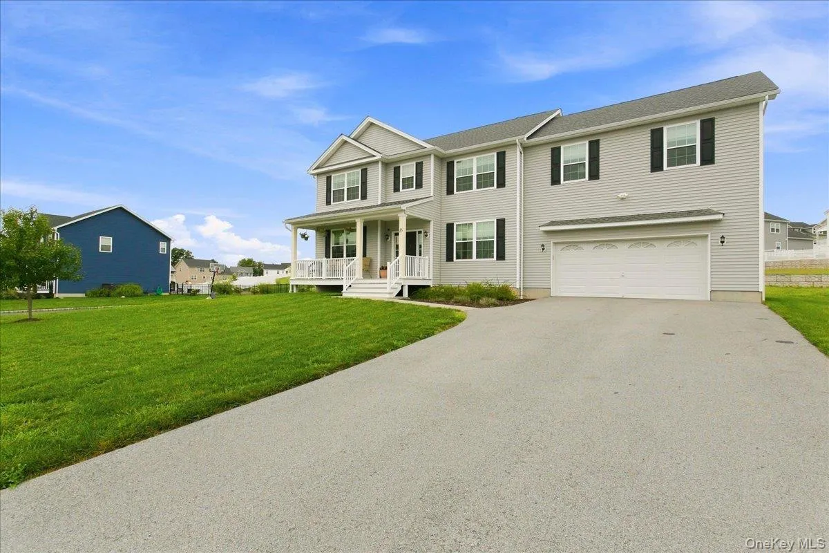 Two-story home with light gray siding, a covered front porch, and a two-car garage Two-story home with light gray siding, a covered front porch, and a two-car garage