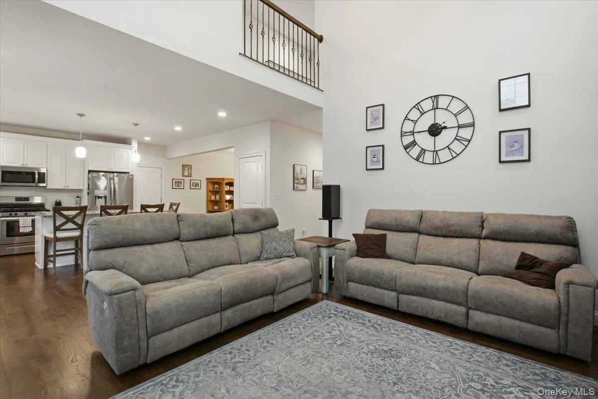 Vaulted ceiling with an open-concept layout, wood-finish flooring, white cabinetry, and stainless steel appliances Vaulted ceiling with an open-concept layout, wood-finish flooring, white cabinetry, and stainless steel appliances