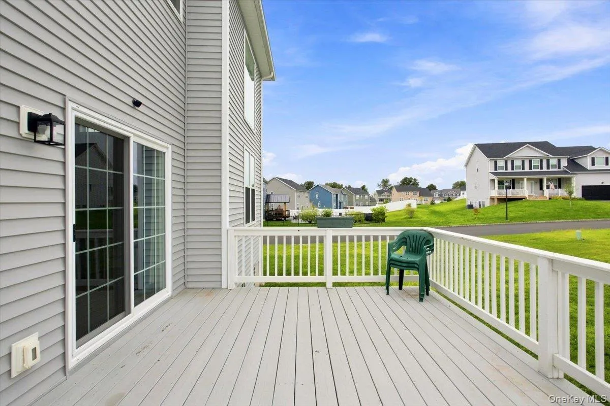 Expansive outdoor deck with white railing, gray siding, and sliding glass door Expansive outdoor deck with white railing, gray siding, and sliding glass door