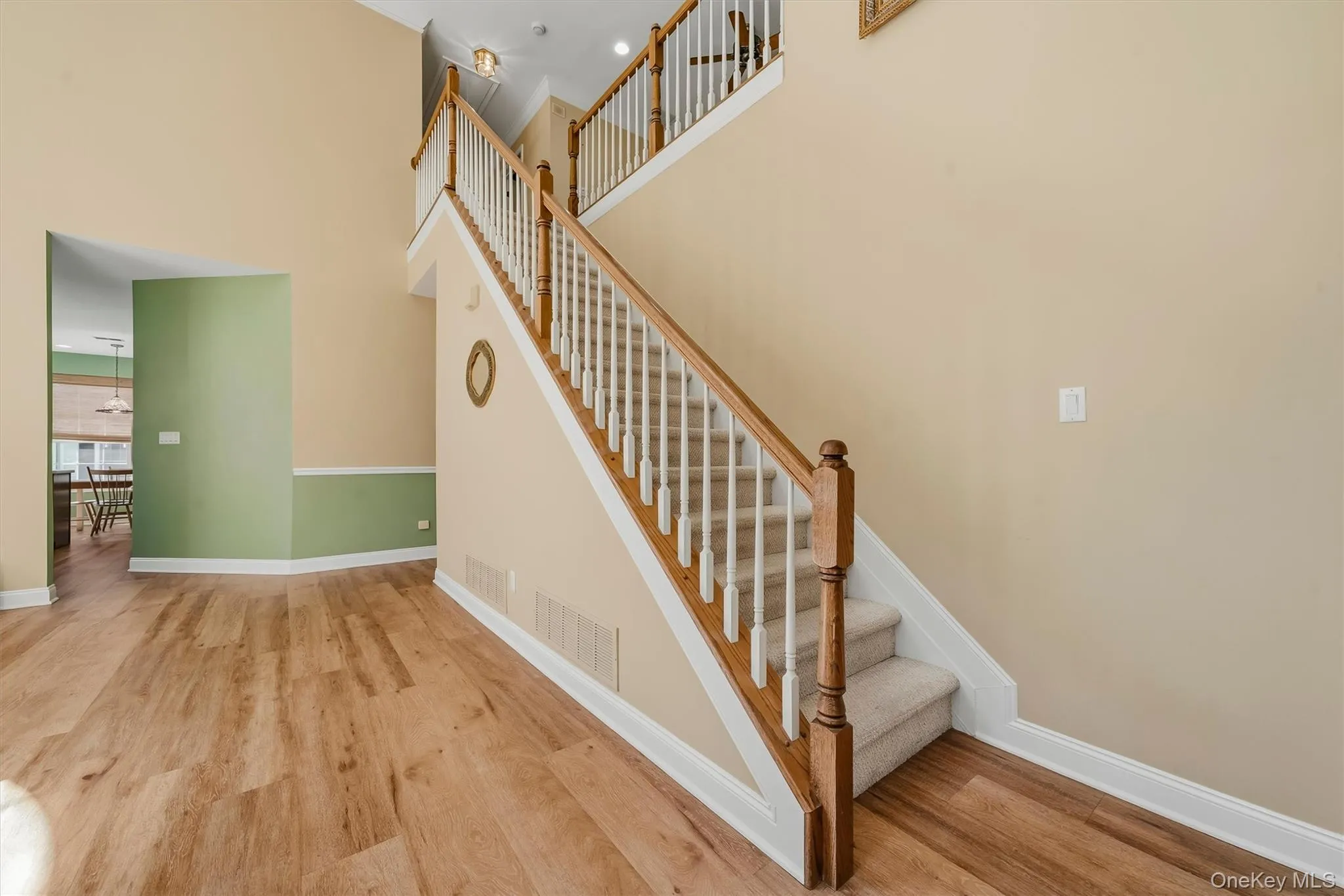 Two-story foyer with vaulted ceilings, wood-finish flooring, and a staircase featuring carpeted treads and wood handrails Two-story foyer with vaulted ceilings, wood-finish flooring, and a staircase featuring carpeted treads and wood handrails