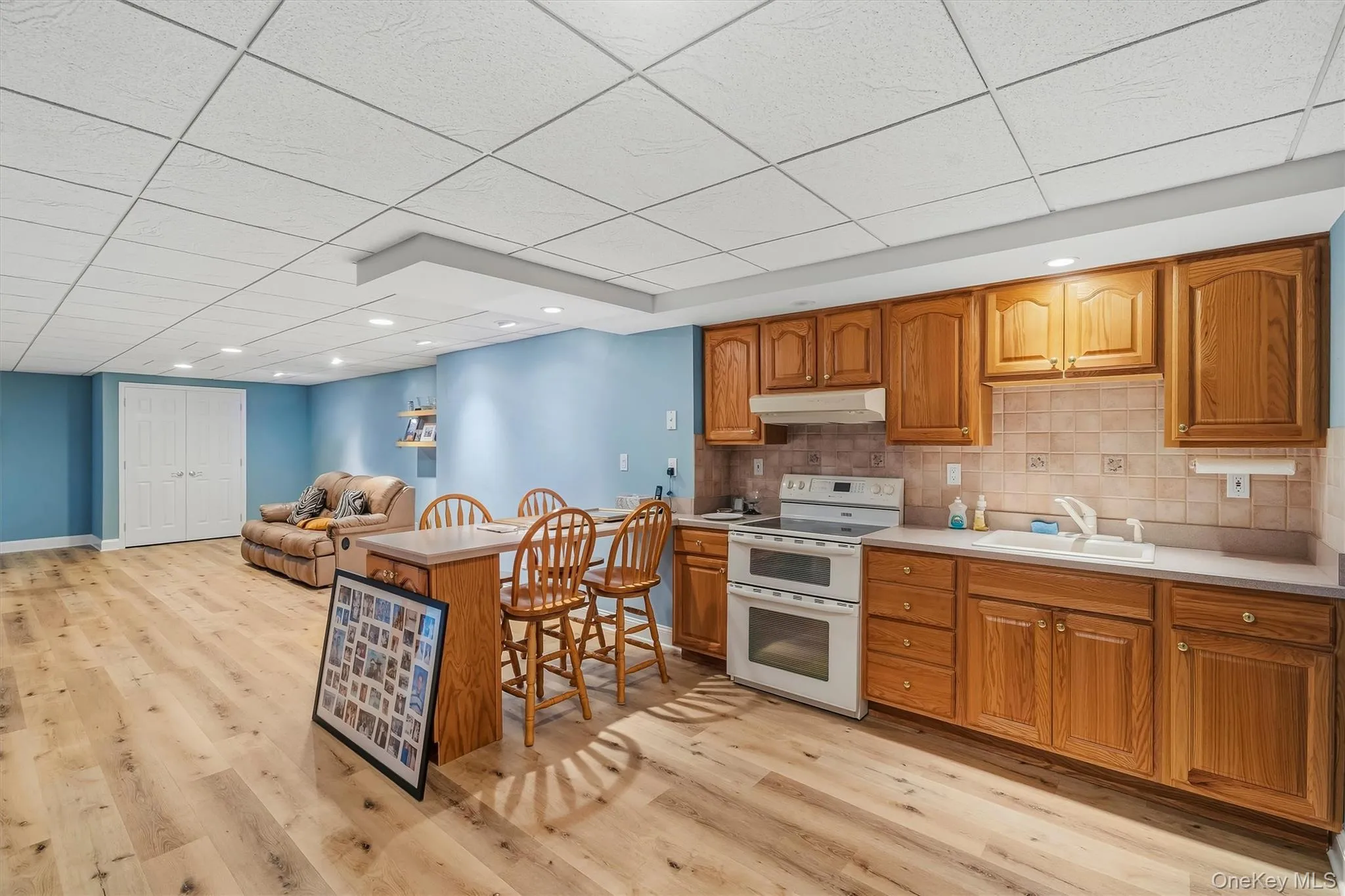 Full kitchen with wood cabinetry, light countertops, and tile backsplash Full kitchen with wood cabinetry, light countertops, and tile backsplash