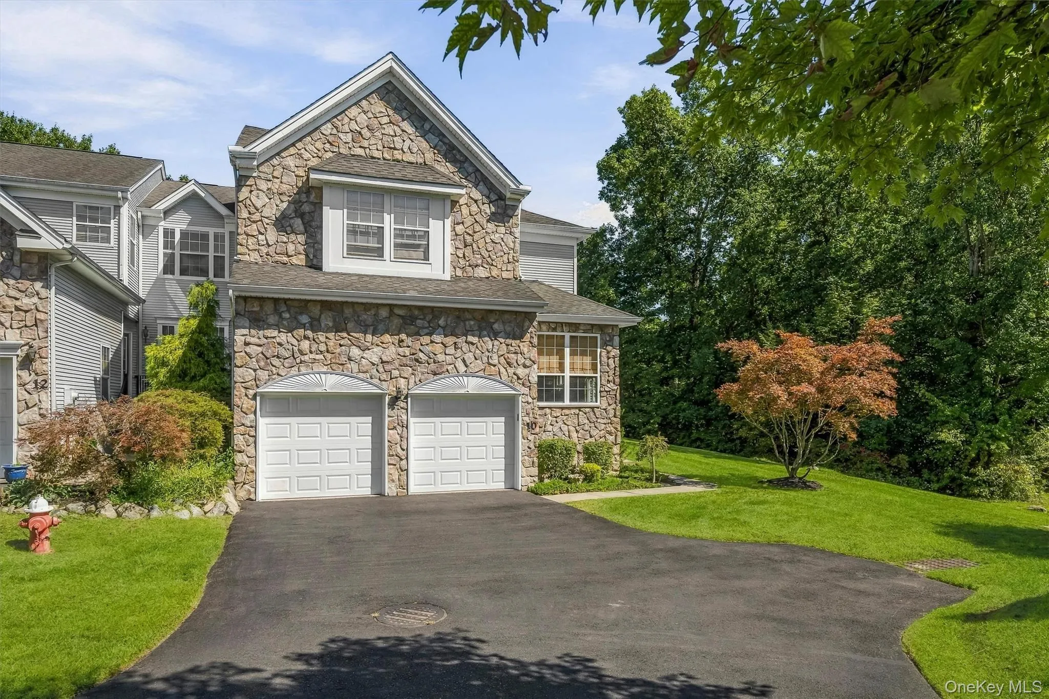Stone exterior with a two-car garage, pitched roofline and dormer window Stone exterior with a two-car garage, pitched roofline and dormer window