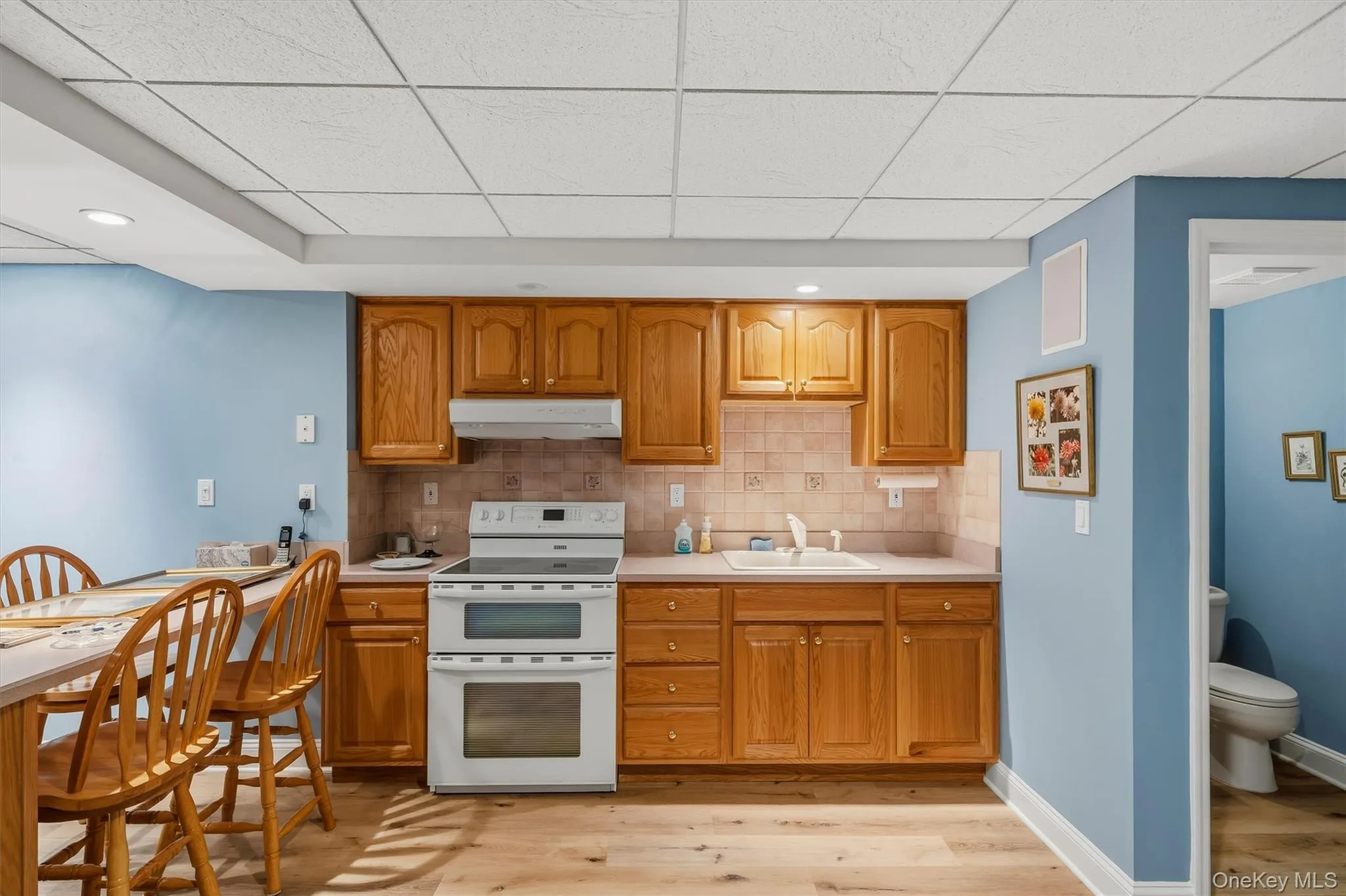 Kitchenette featuring wood-finish cabinetry, a ceramic tile backsplash, and a double oven range Kitchenette featuring wood-finish cabinetry, a ceramic tile backsplash, and a double oven range