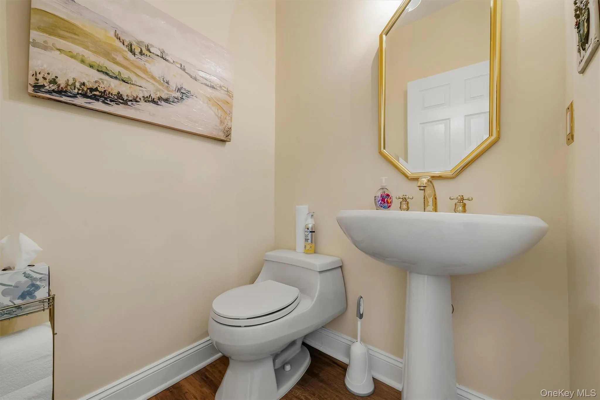 Wood-finish flooring, pedestal sink, and gold-finish fixtures Wood-finish flooring, pedestal sink, and gold-finish fixtures