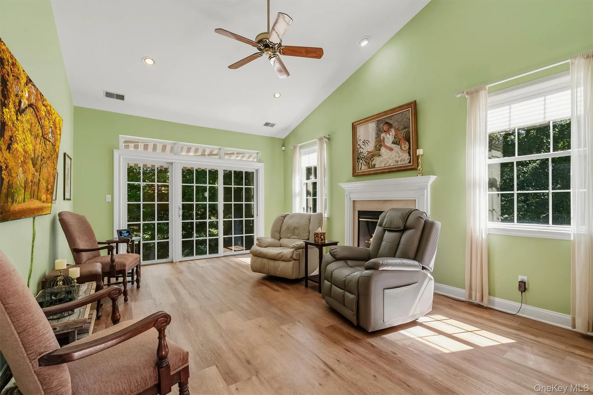 Vaulted ceiling with a ceiling fan and recessed lighting, wood-finish flooring, a white fireplace mantel, and sliding glass doors Vaulted ceiling with a ceiling fan and recessed lighting, wood-finish flooring, a white fireplace mantel, and sliding glass doors
