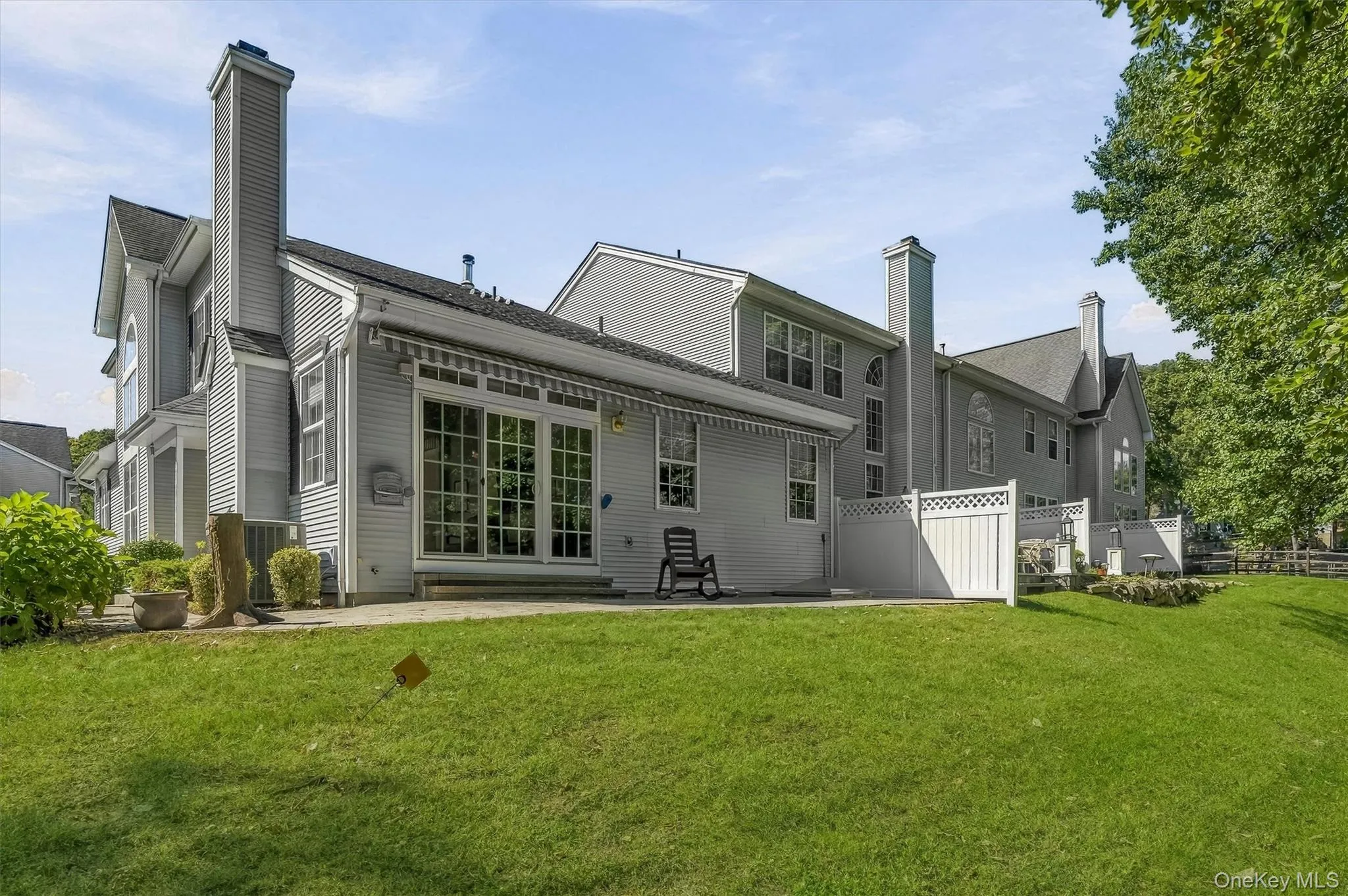 Rear exterior featuring a large patio, extensive lawn, and white privacy fencing Rear exterior featuring a large patio, extensive lawn, and white privacy fencing