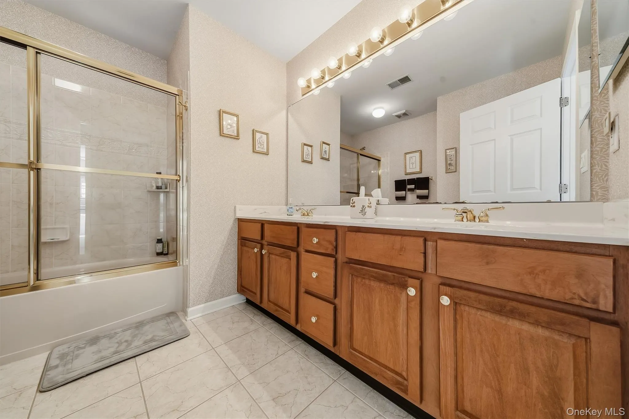 Double vanity with wood-finish cabinetry and gold-tone fixtures Double vanity with wood-finish cabinetry and gold-tone fixtures