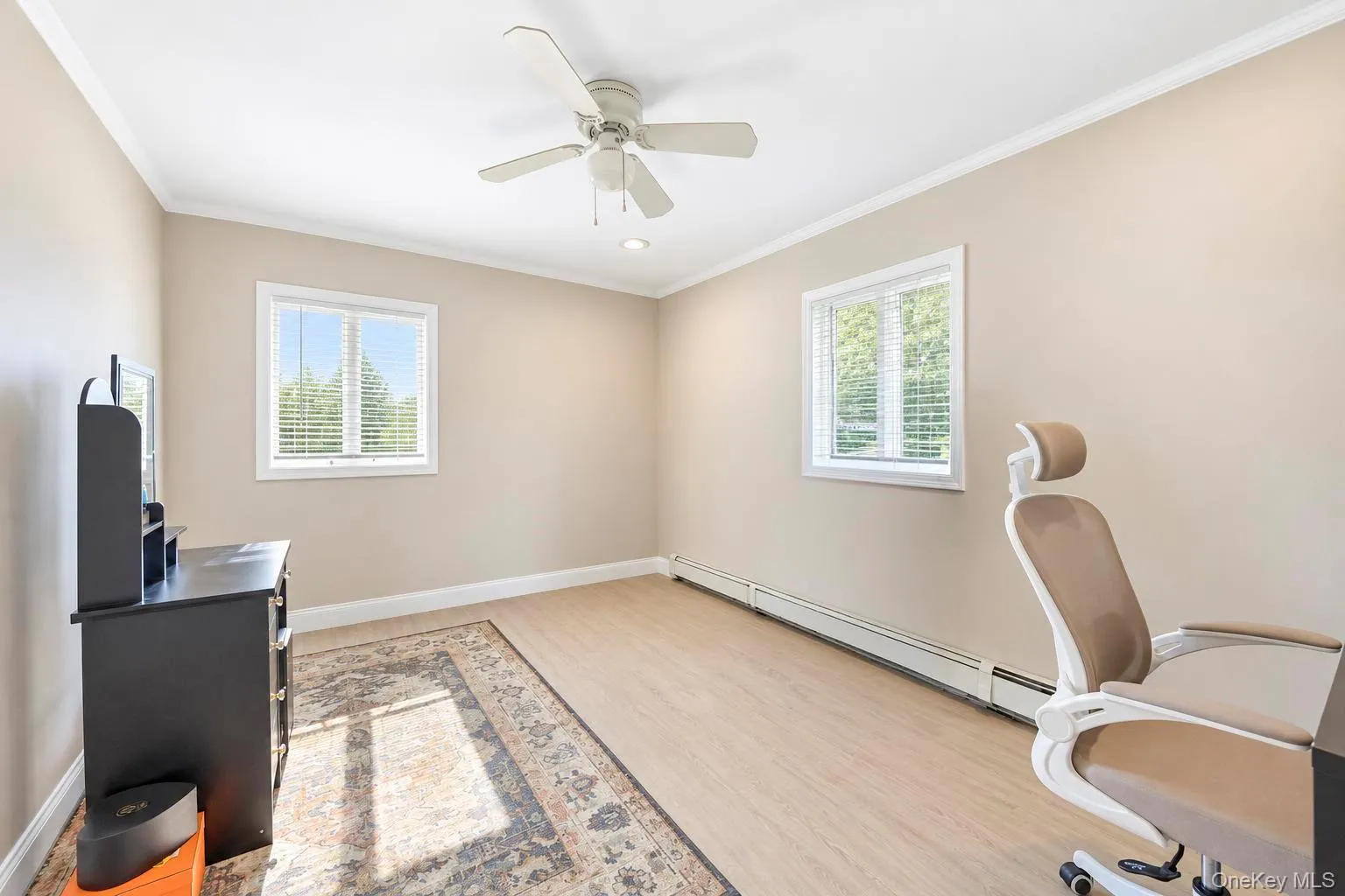 Light wood-finish flooring, two large windows with blinds, ceiling fan with integrated lighting, and warm neutral wall tones Light wood-finish flooring, two large windows with blinds, ceiling fan with integrated lighting, and warm neutral wall tones