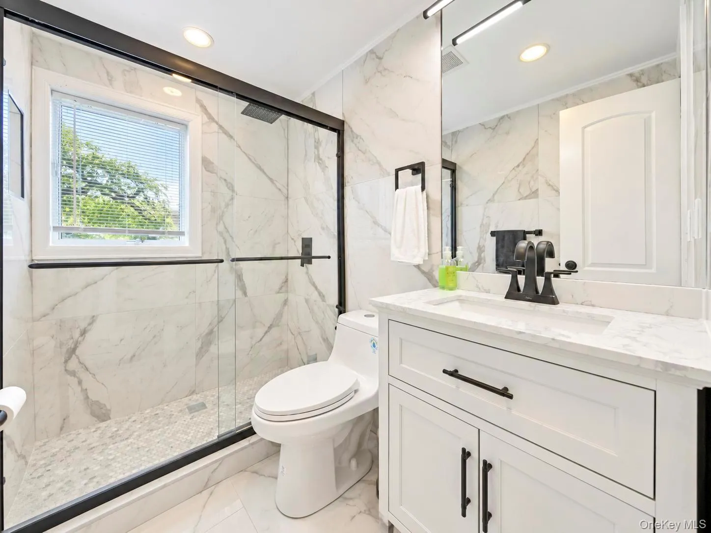 White vanity with a stone countertop, an integrated sink, and black fixtures White vanity with a stone countertop, an integrated sink, and black fixtures