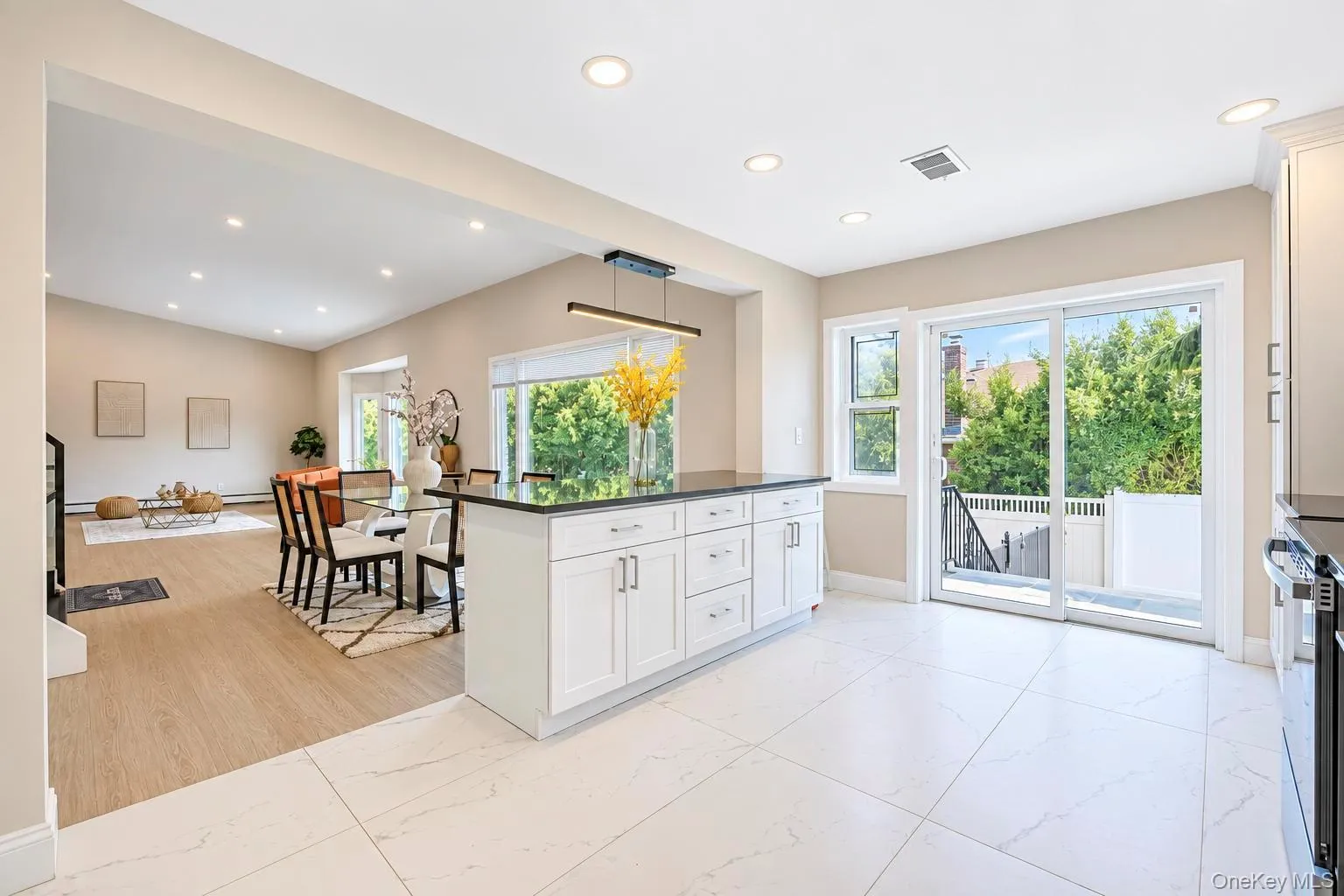 Open-concept interior featuring a kitchen island with dark countertops, white cabinetry, and recessed lighting Open-concept interior featuring a kitchen island with dark countertops, white cabinetry, and recessed lighting