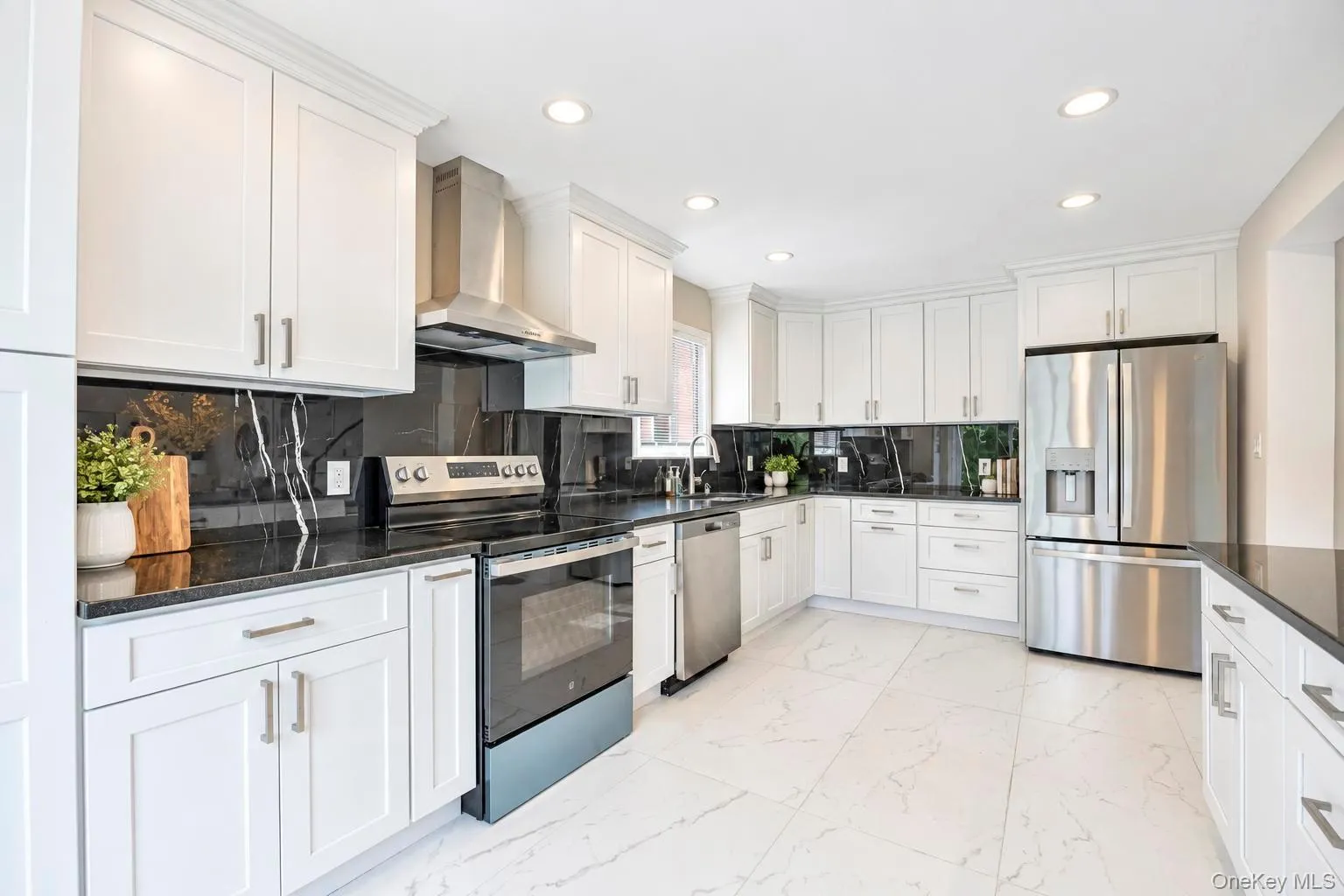 Modern kitchen featuring white cabinetry, dark countertops, a dark veined backsplash, stainless steel appliances, and recessed lighting Modern kitchen featuring white cabinetry, dark countertops, a dark veined backsplash, stainless steel appliances, and recessed lighting