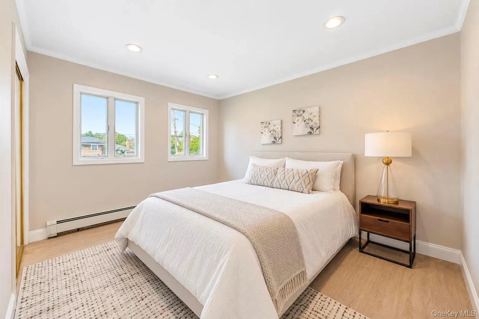 Recessed lighting, crown molding, two windows with white trim, light wood-finish flooring, and a built-in closet with bifold doors Recessed lighting, crown molding, two windows with white trim, light wood-finish flooring, and a built-in closet with bifold doors