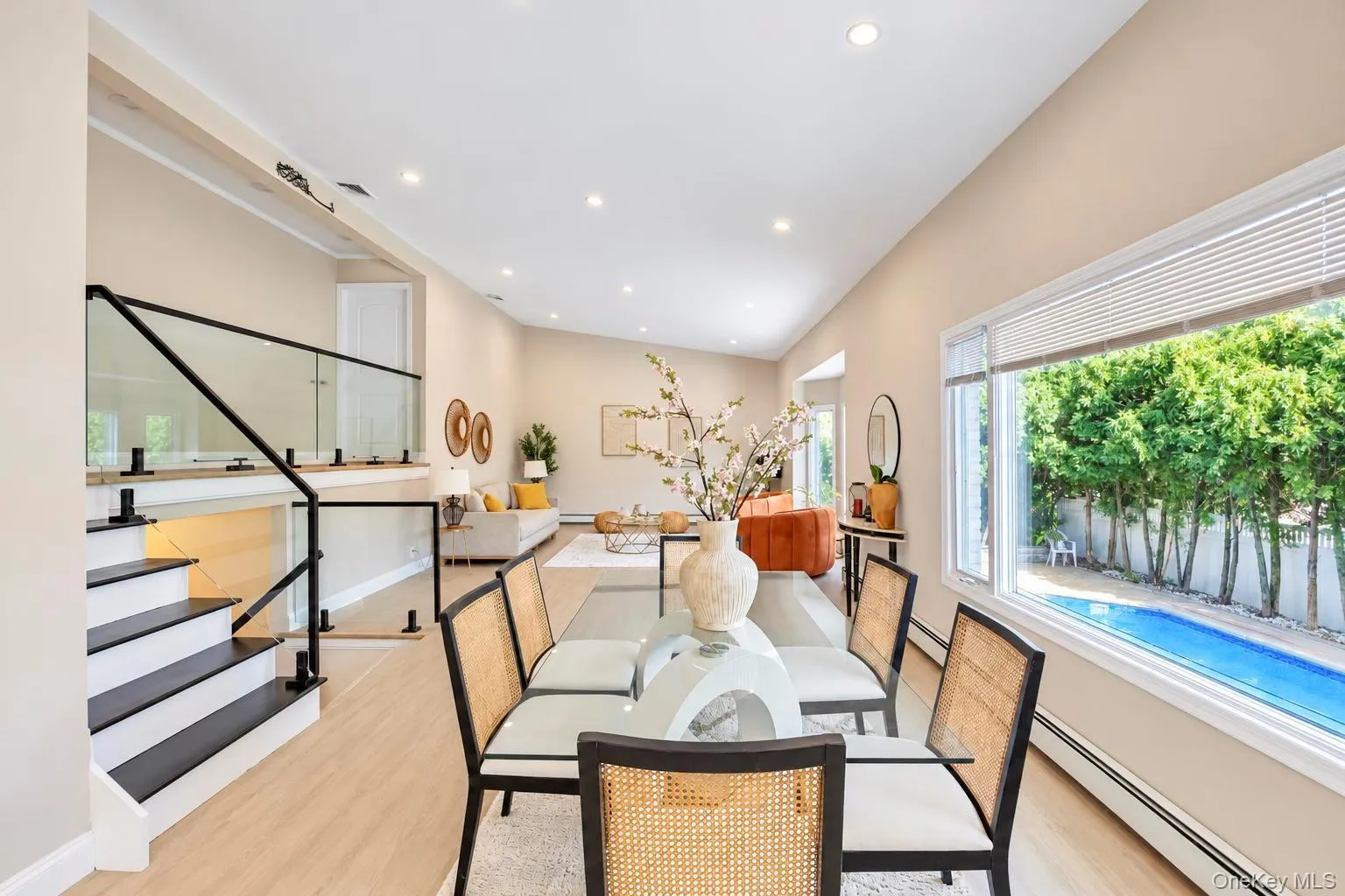 Recessed lighting, wood-finish flooring, and a glass panel staircase with black railings Recessed lighting, wood-finish flooring, and a glass panel staircase with black railings