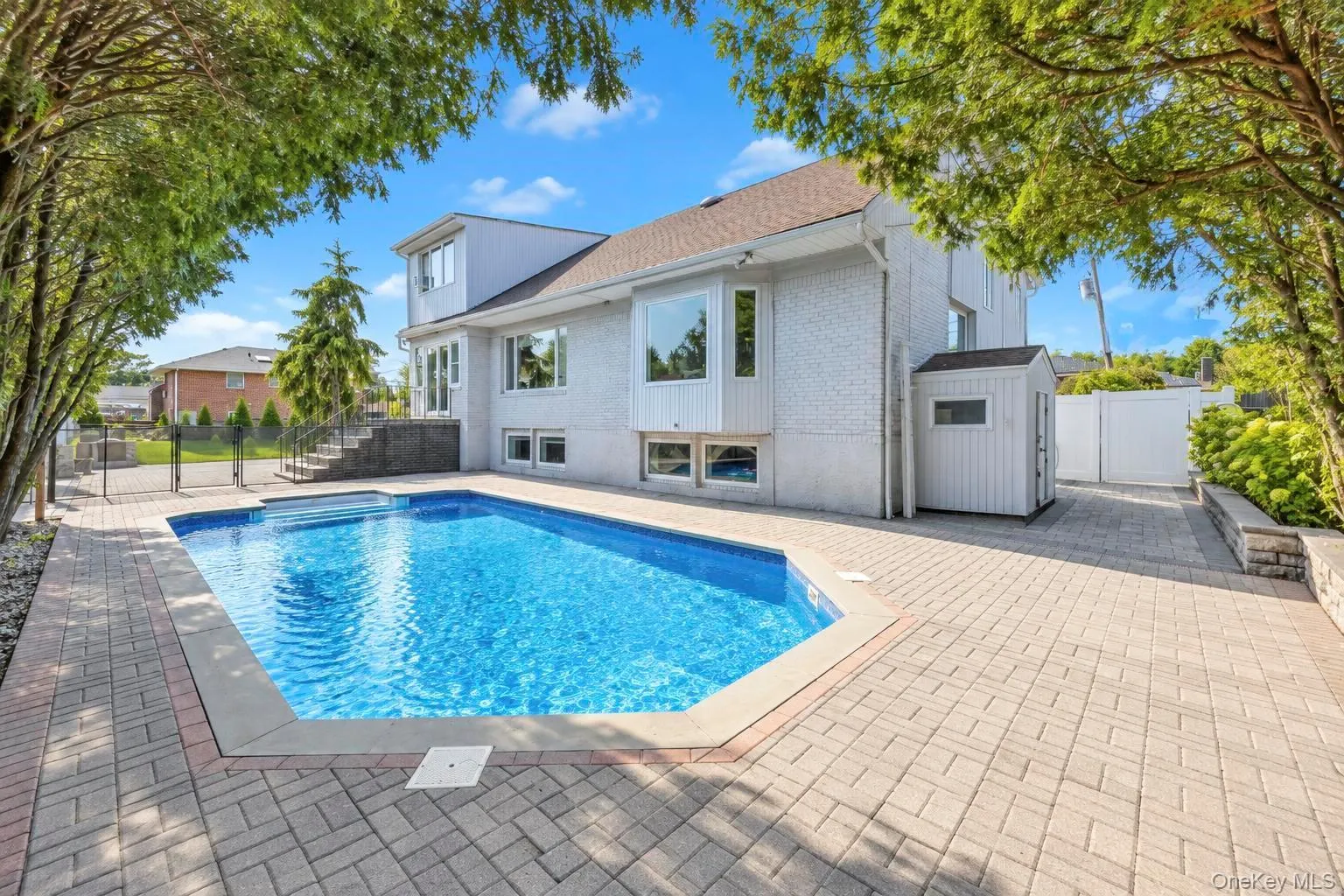 In-ground swimming pool with a surrounding paver patio and a privacy fence In-ground swimming pool with a surrounding paver patio and a privacy fence
